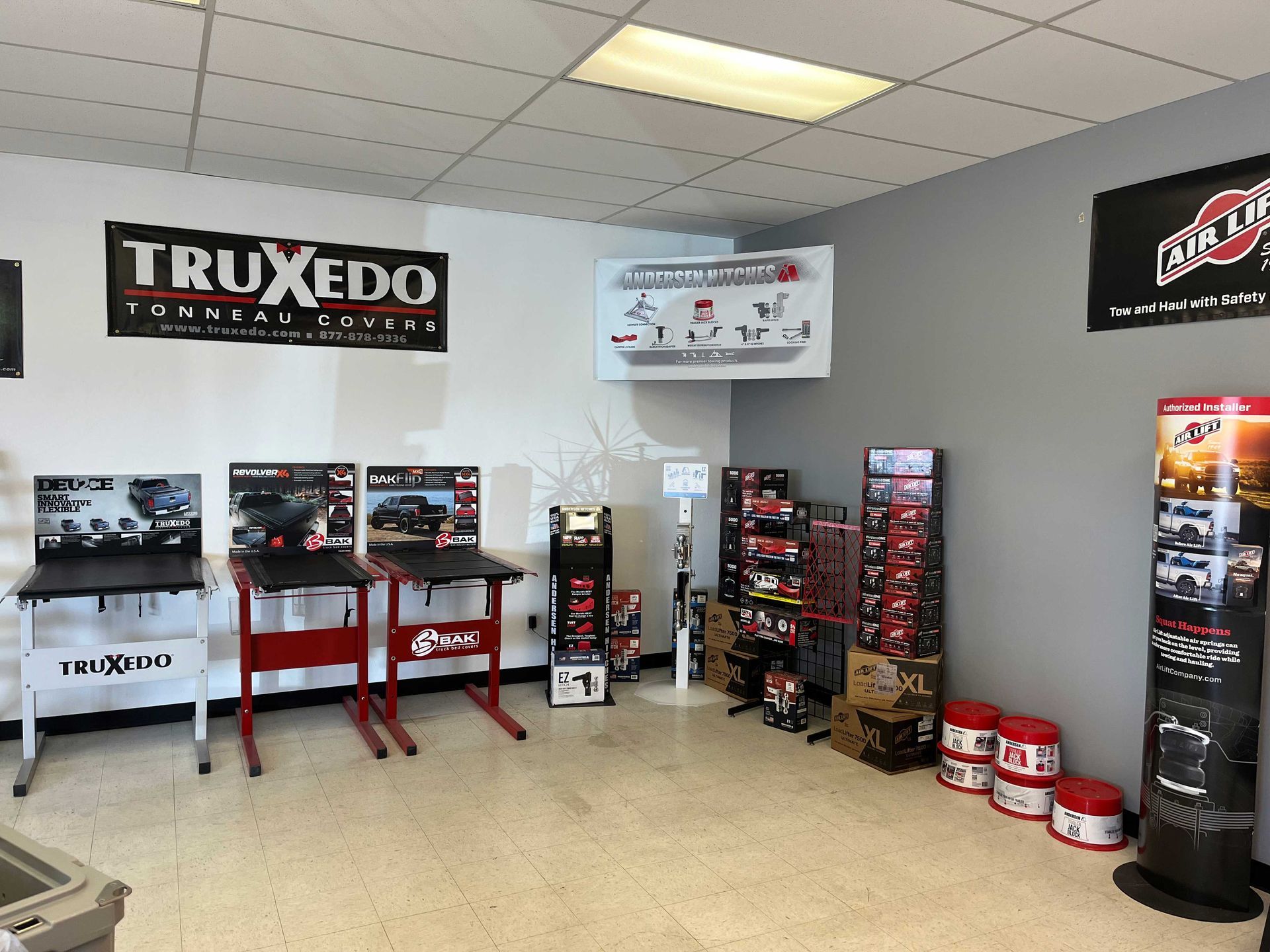 A showroom featuring truck bed cover displays, including TruXedo and Access Roll-Up Cover branded stands and marketing.