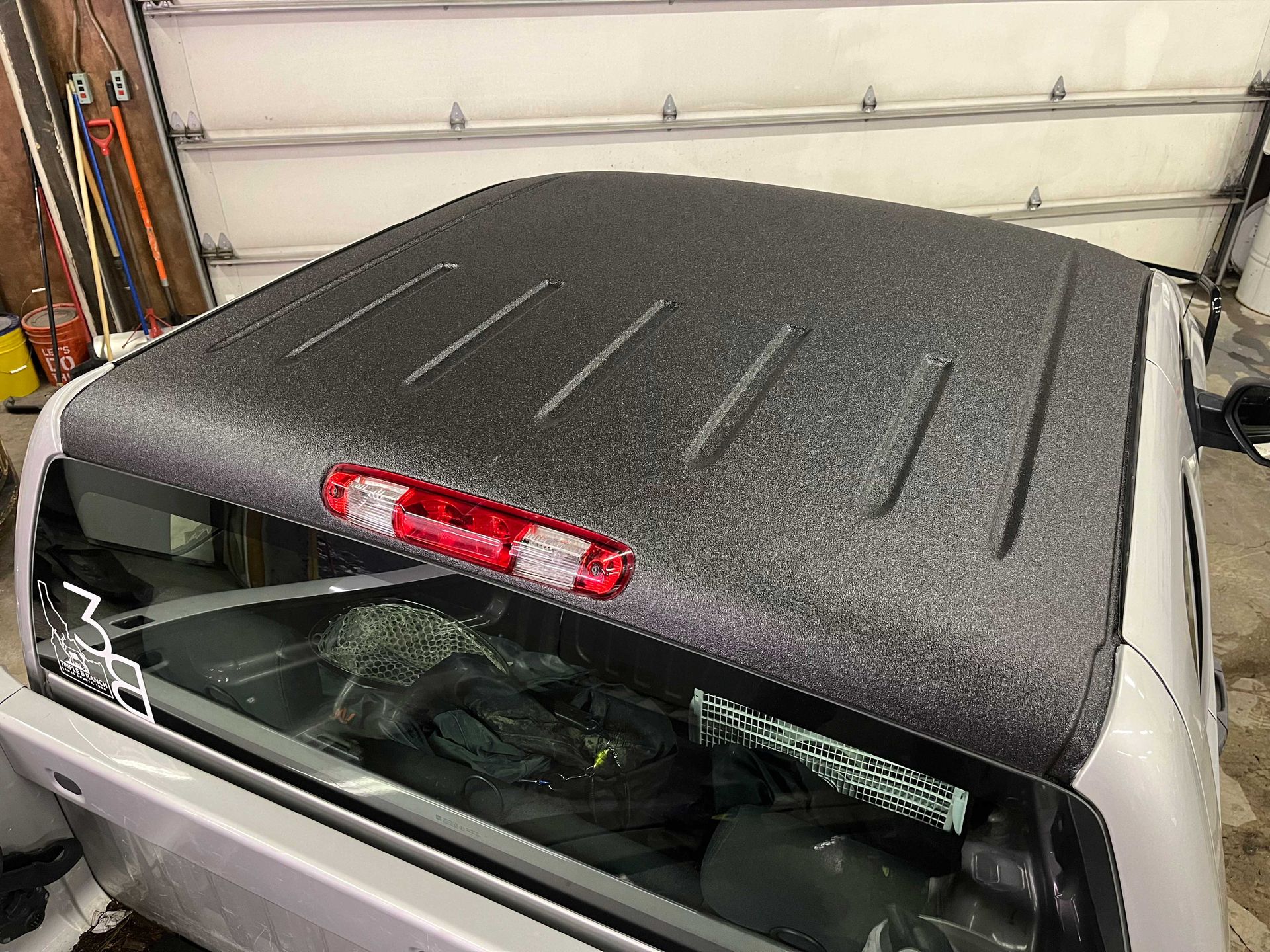 A textured, black, spray-on coated truck roof with a centered red third brake light above the rear window.
