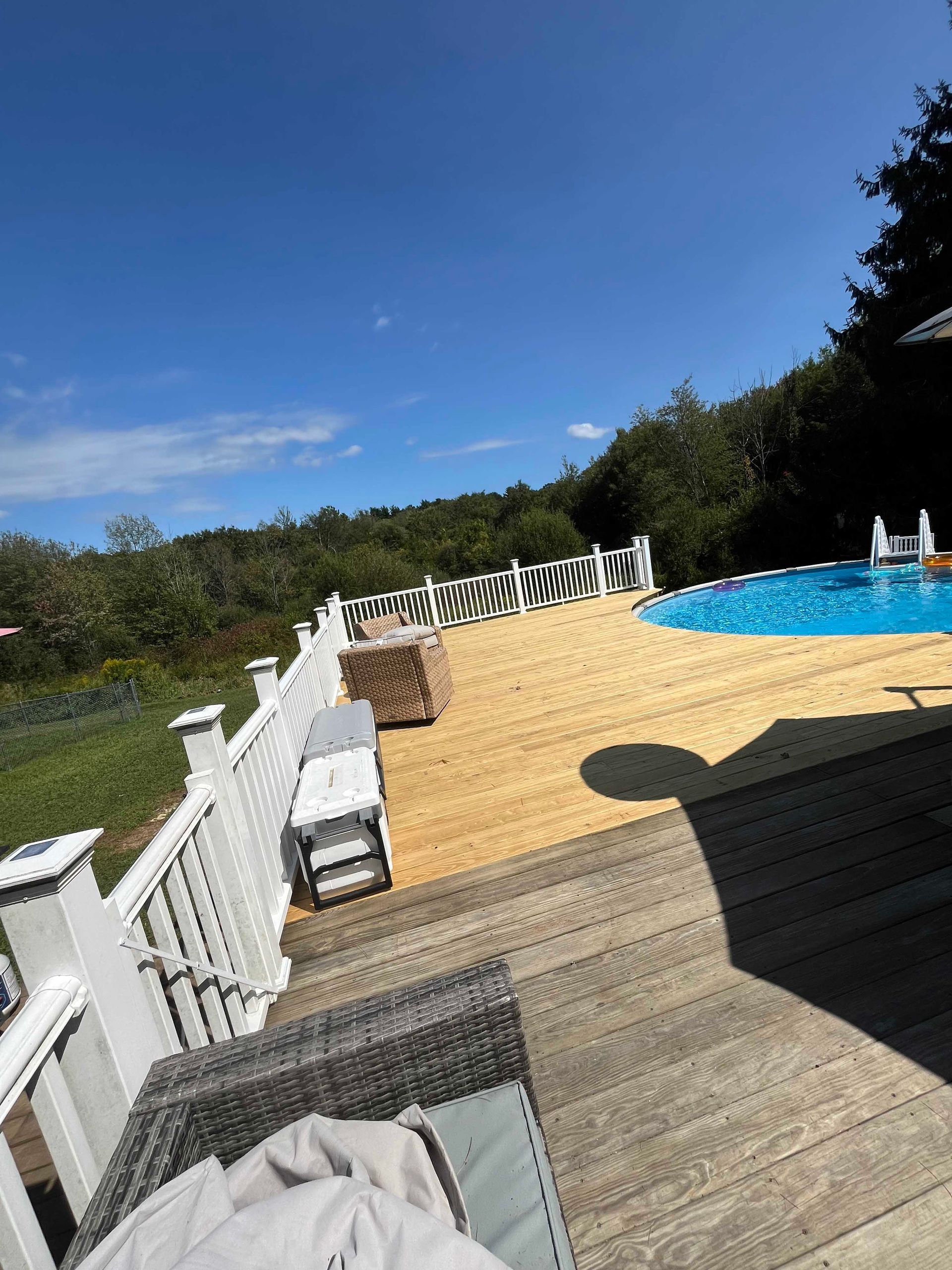 A wooden deck with a swimming pool in the background