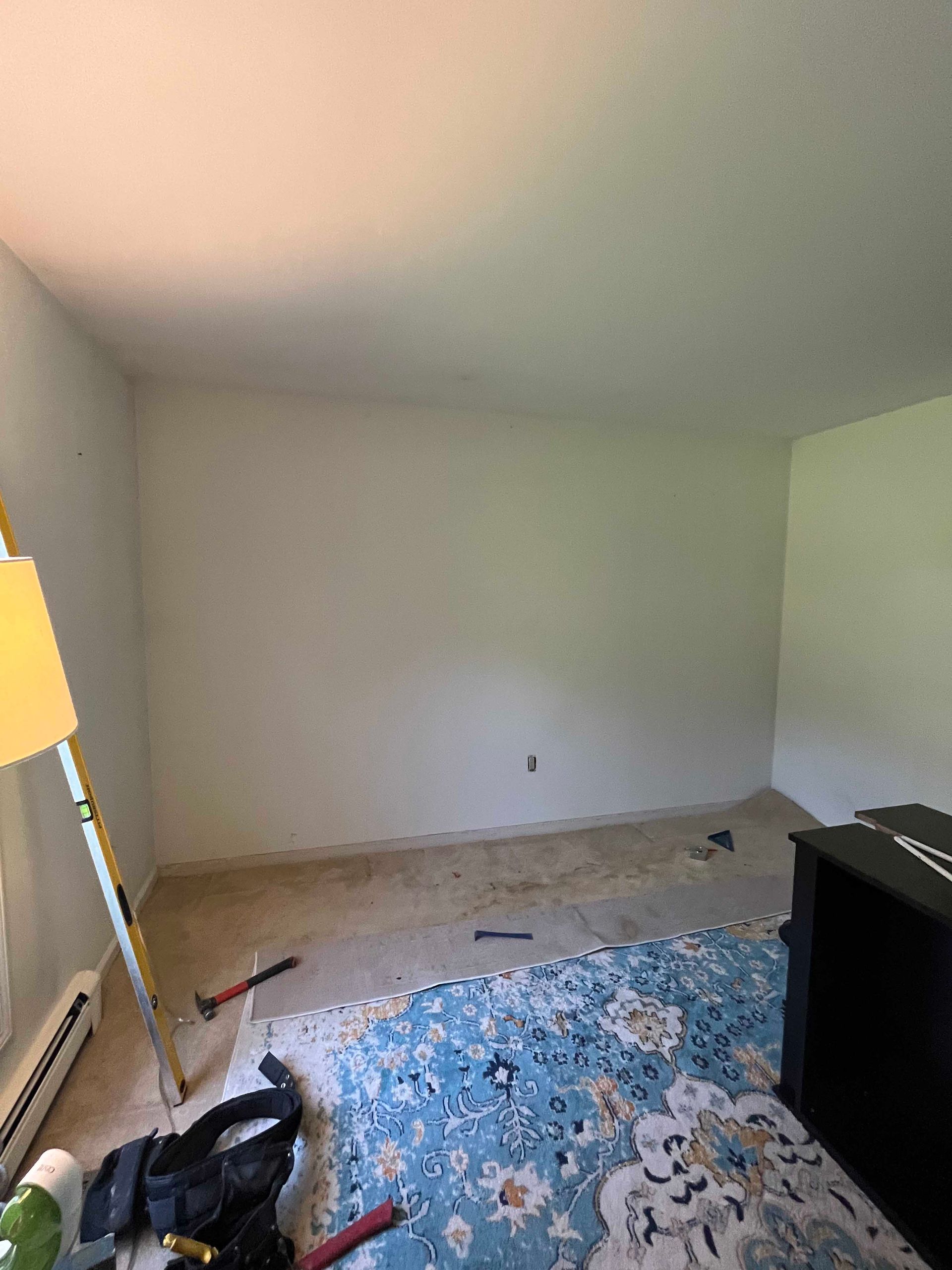 An empty room with a rug and a lamp.