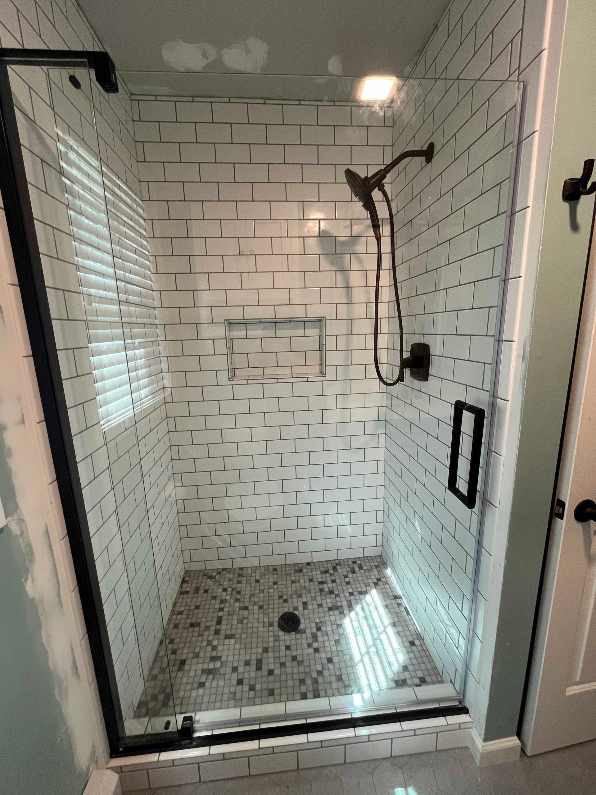 A shower with white brick walls and a glass door