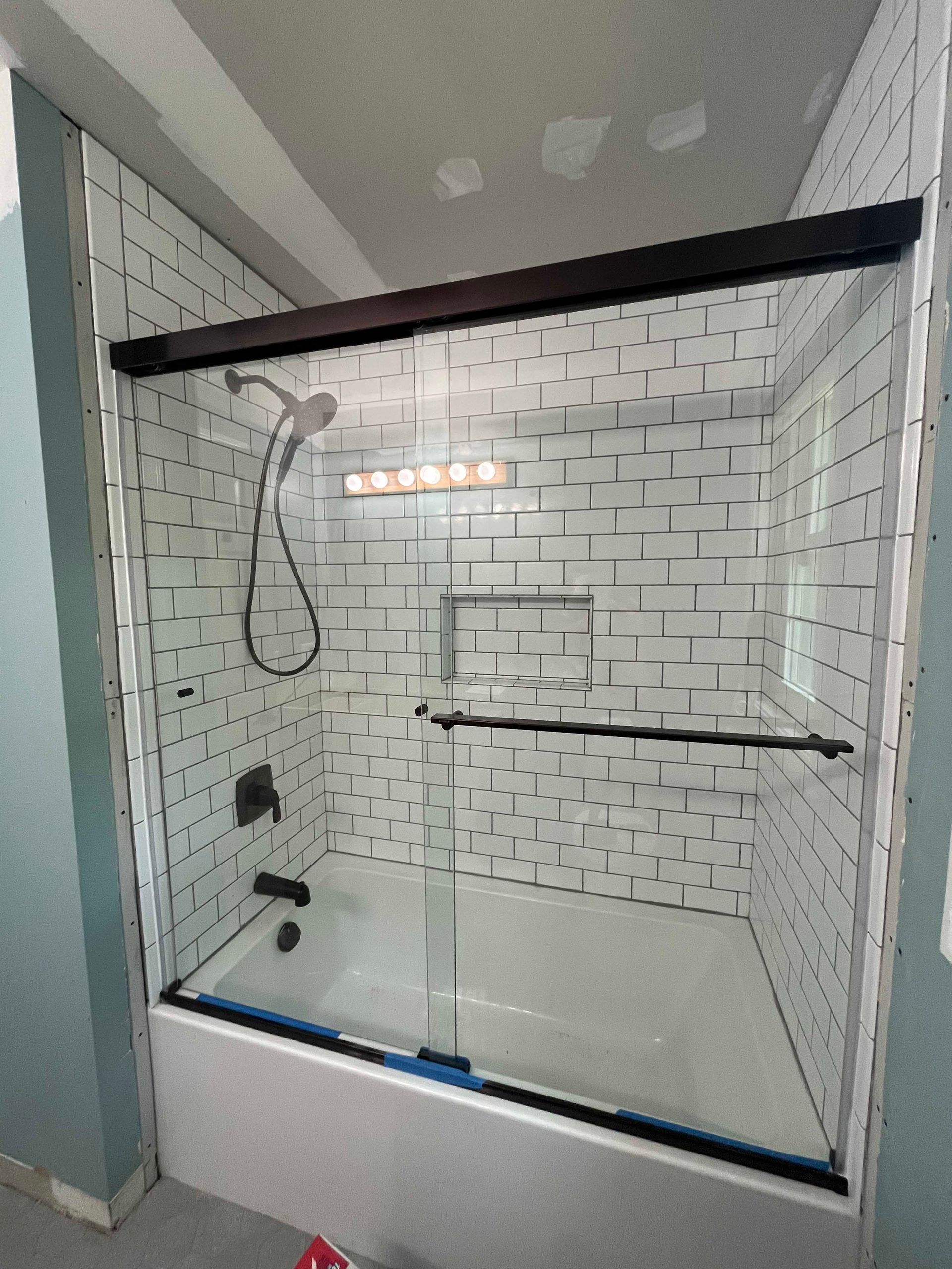 A bathroom with a bathtub and a shower with a sliding glass door