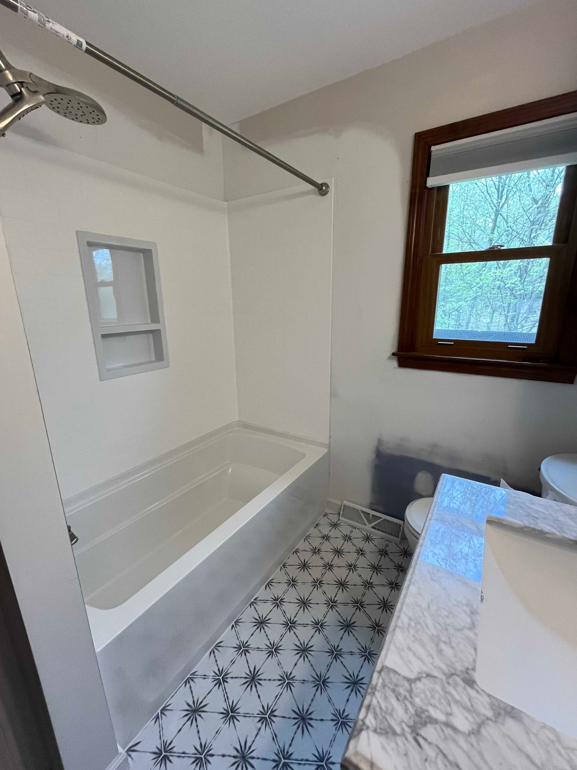 A bathroom with a bathtub , sink , toilet and window.