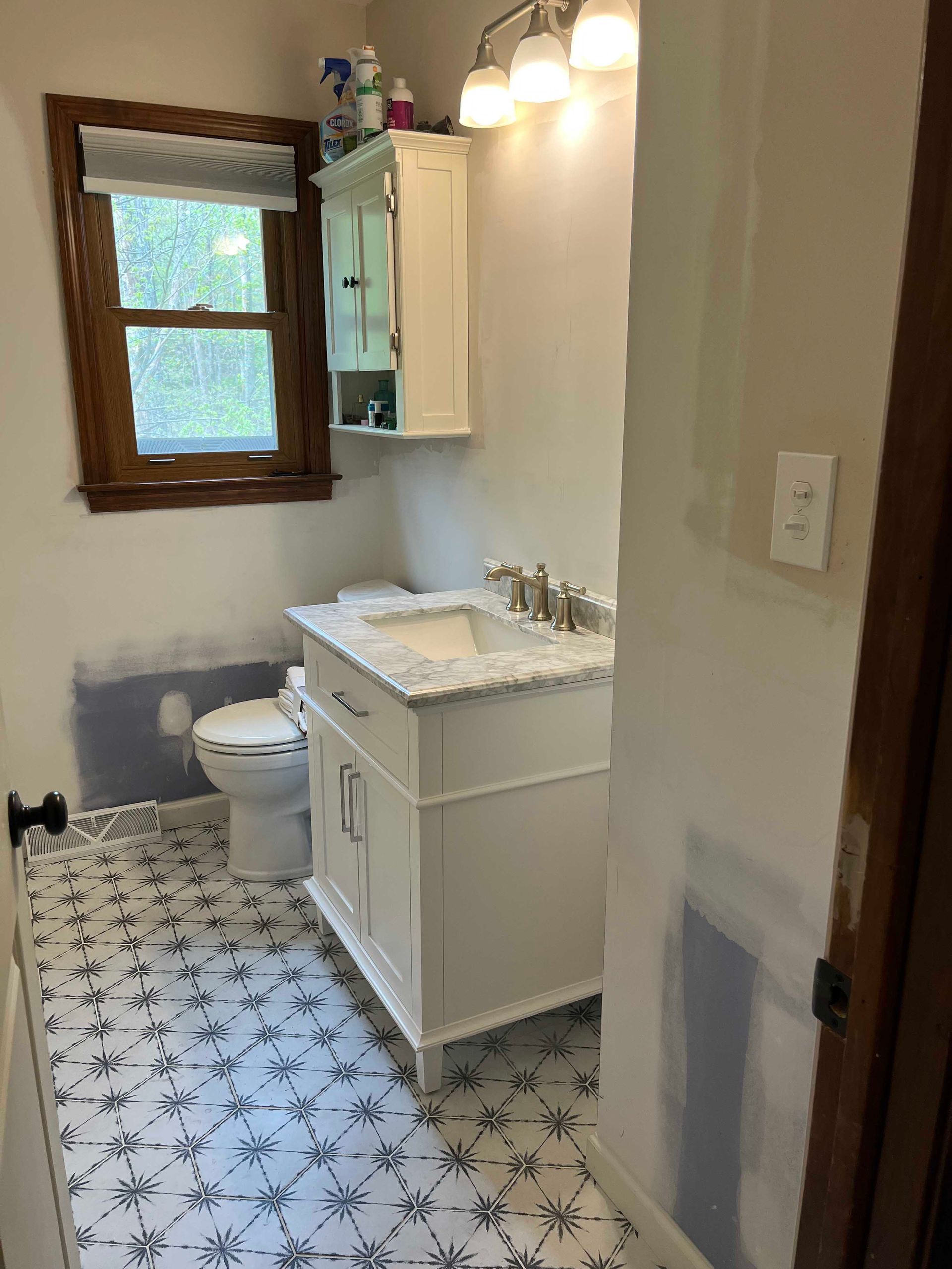 A bathroom with a sink , toilet and window.