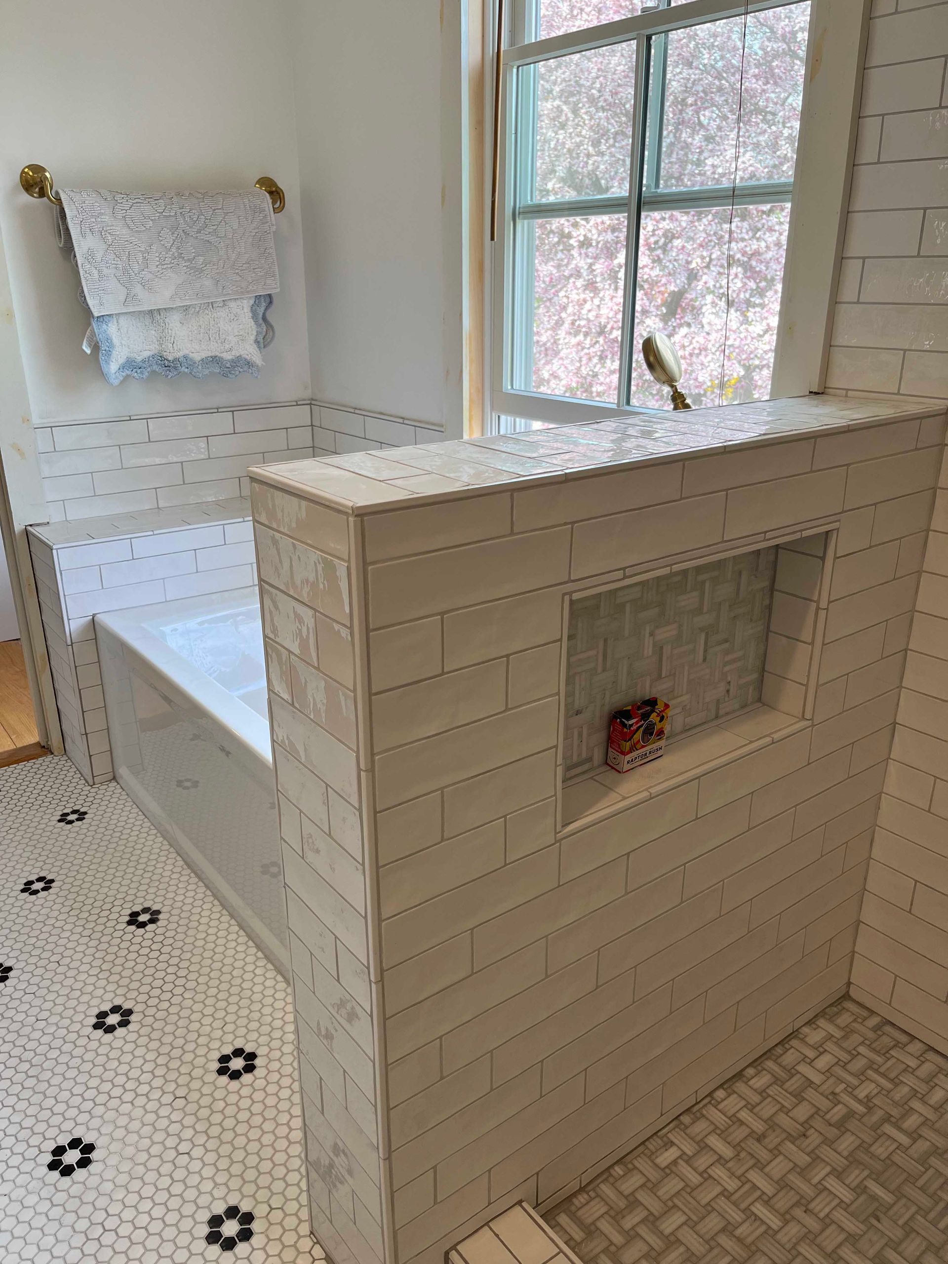 A bathroom with a bathtub , shower , and window.