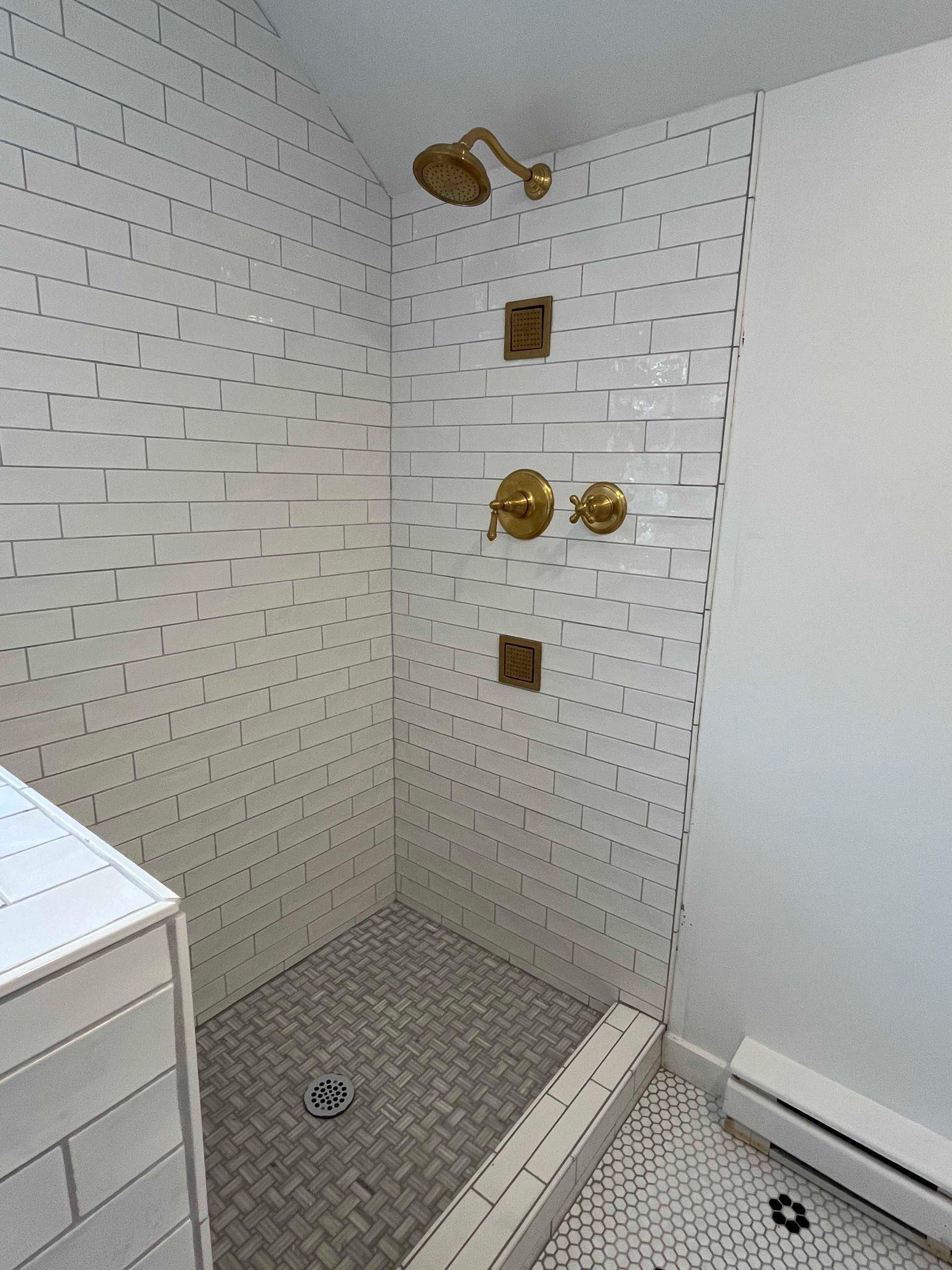 A bathroom with a walk in shower and a brick wall.