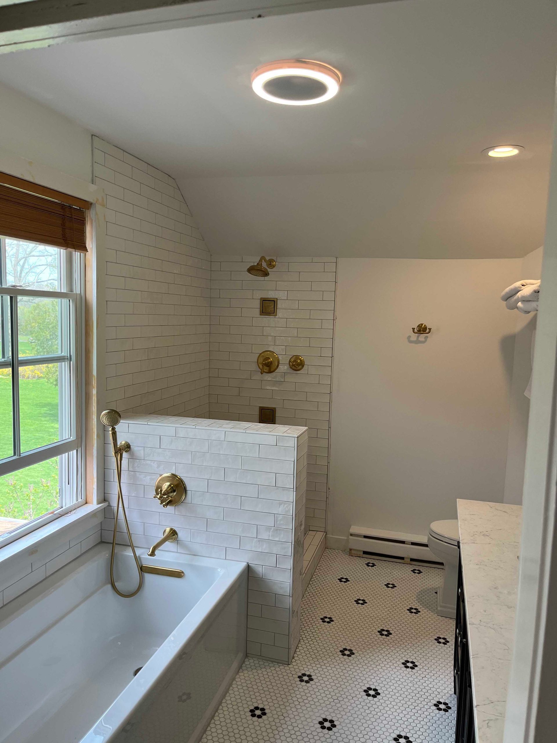 A bathroom with a bathtub , toilet , shower and window.