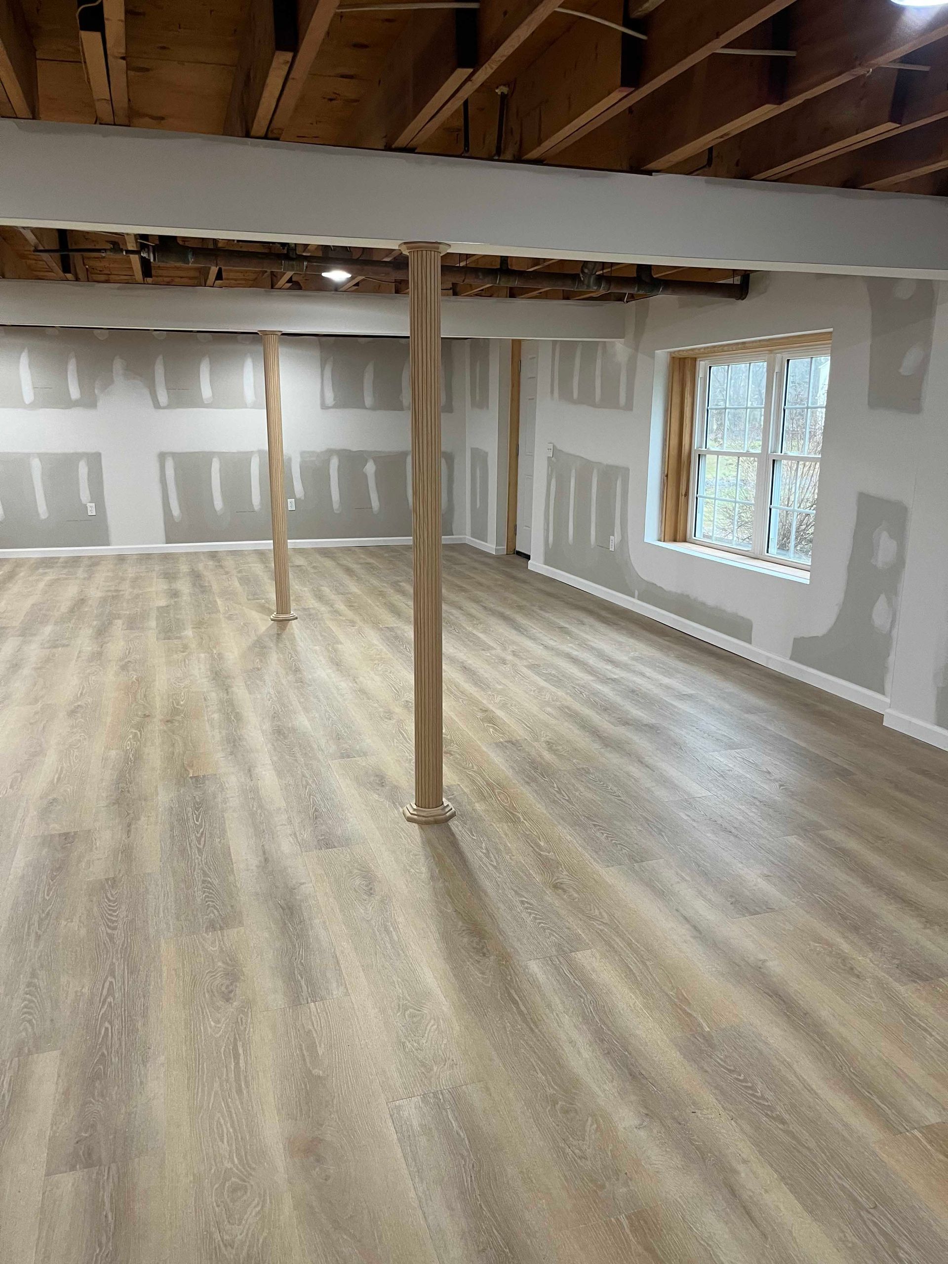 An empty room with a wooden floor and a wooden pole in the middle.