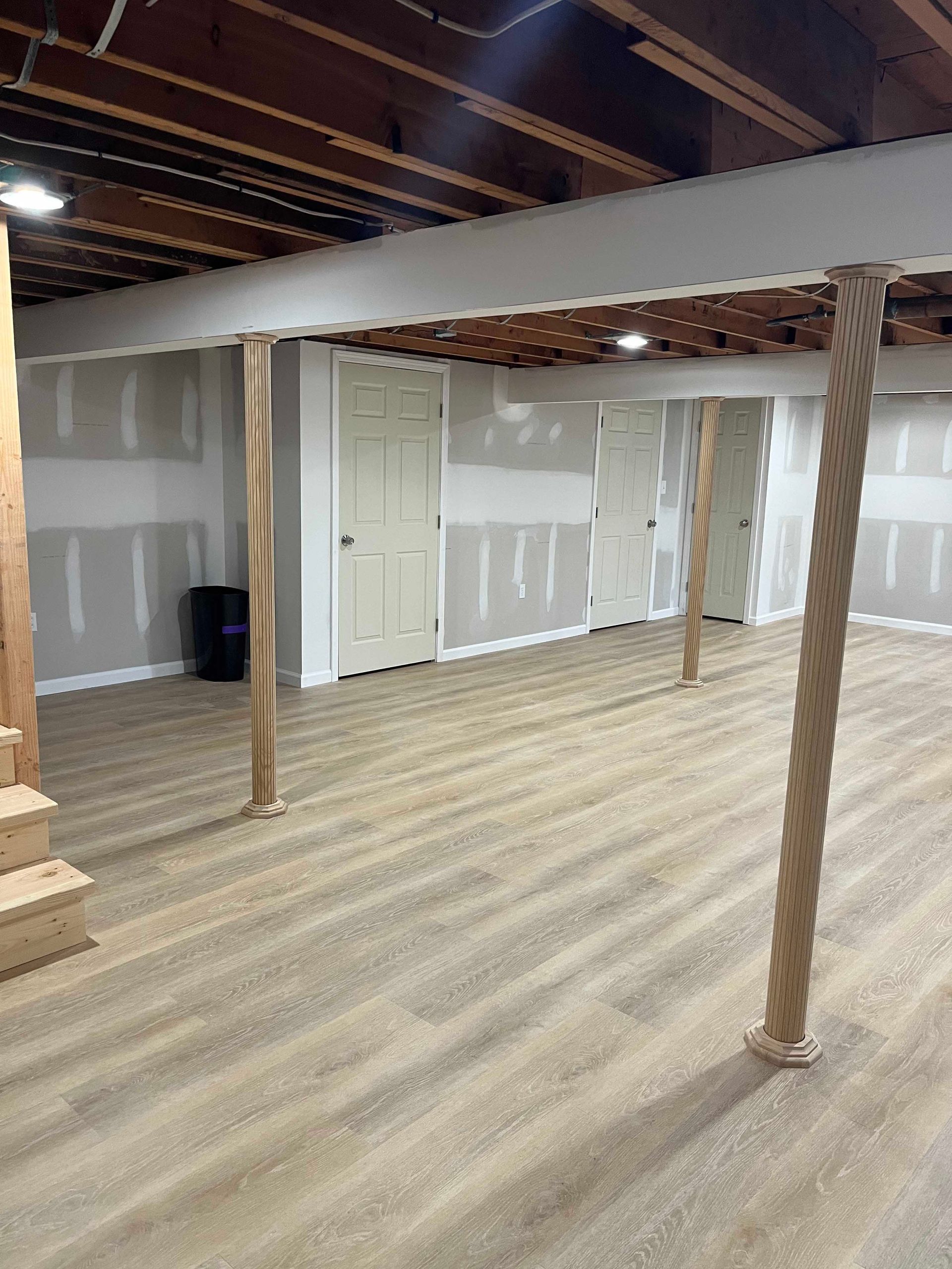An empty basement with a wooden floor and stairs.