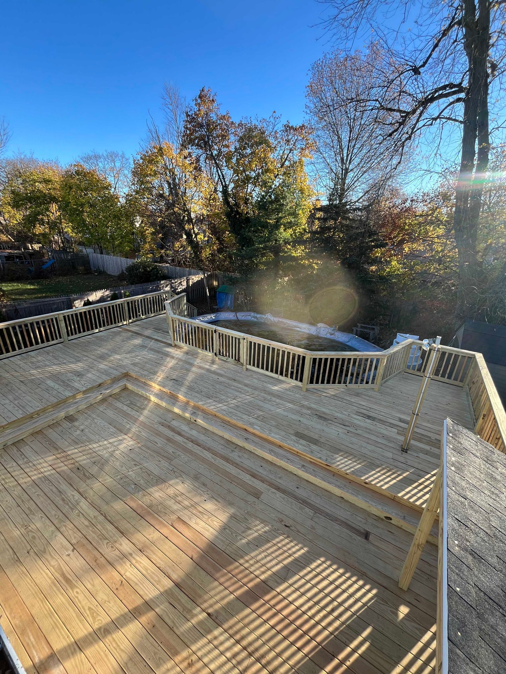 A wooden deck is being built on a sunny day with trees in the background.