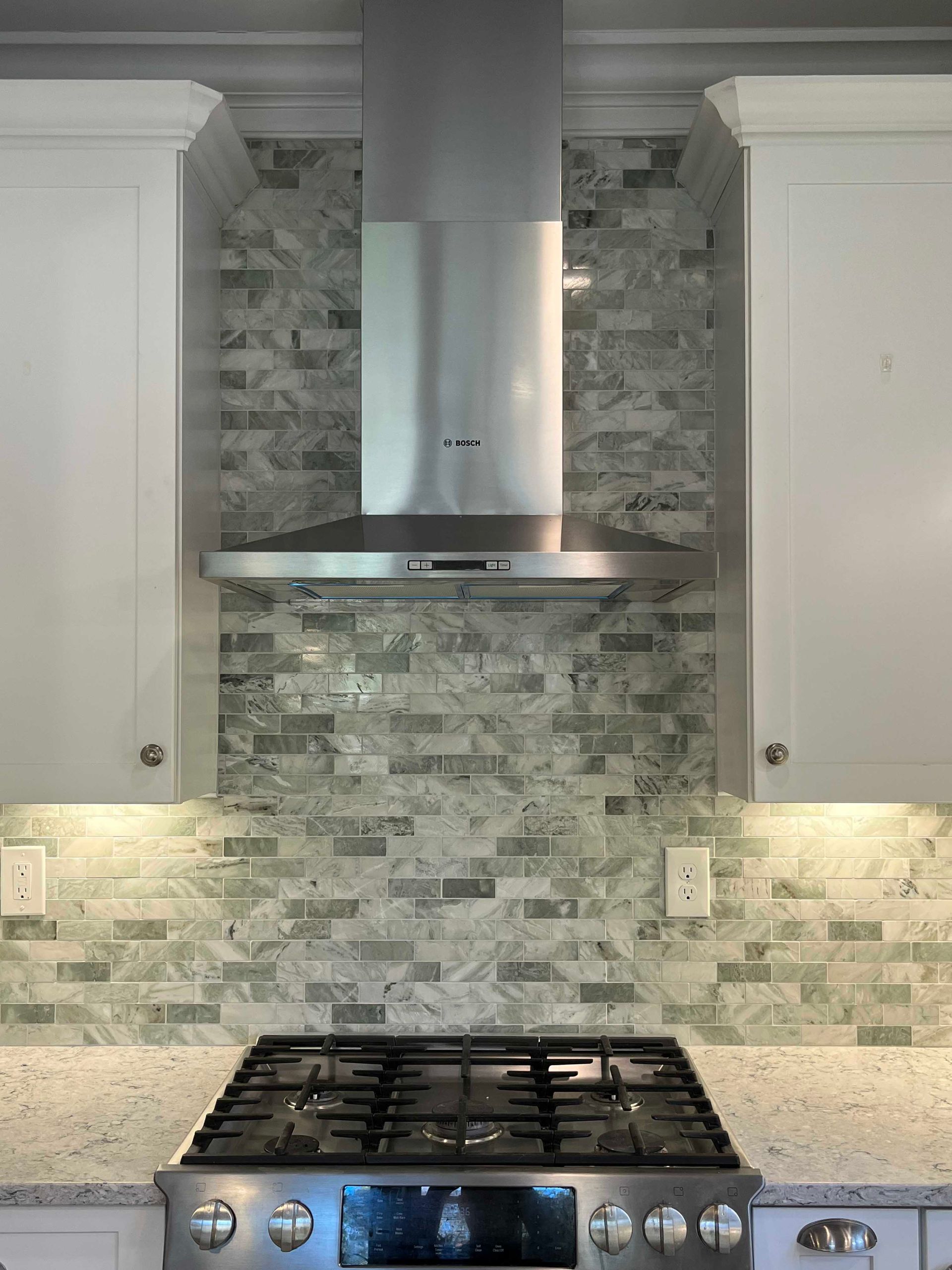 A kitchen with a stove top oven and a hood above it.