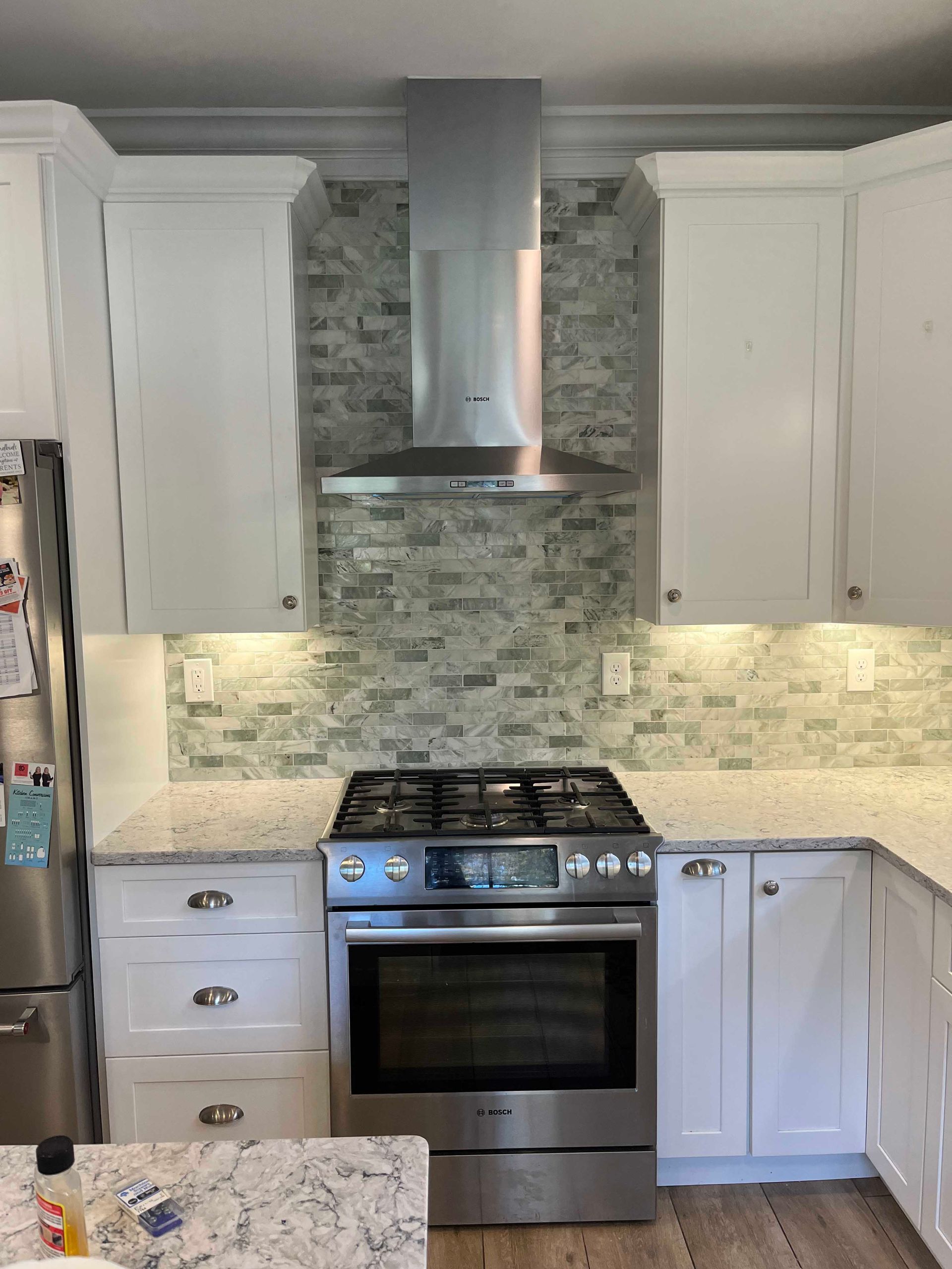 A kitchen with stainless steel appliances and white cabinets.