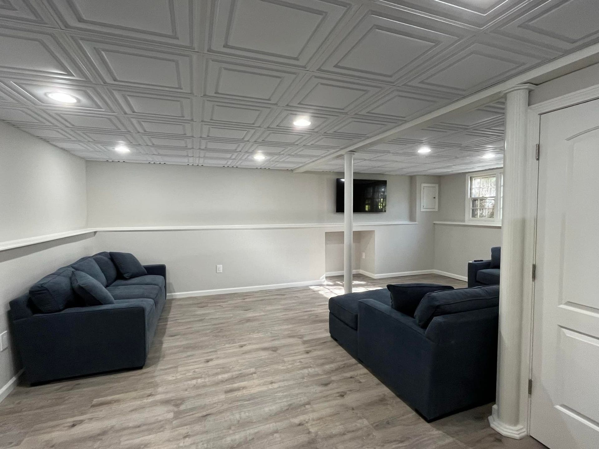 A living room in a basement with two couches and a television.