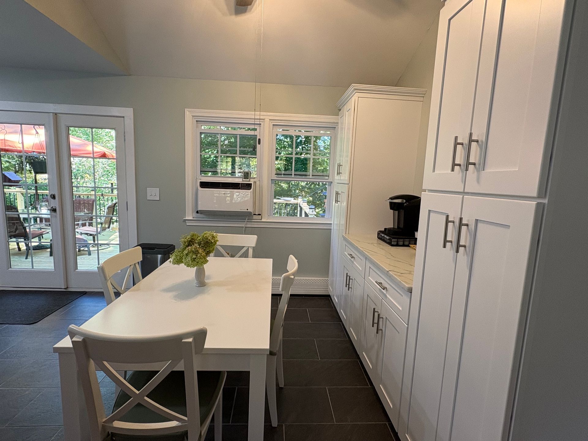 White kitchen with table, cabinets, and a doorway to a patio.