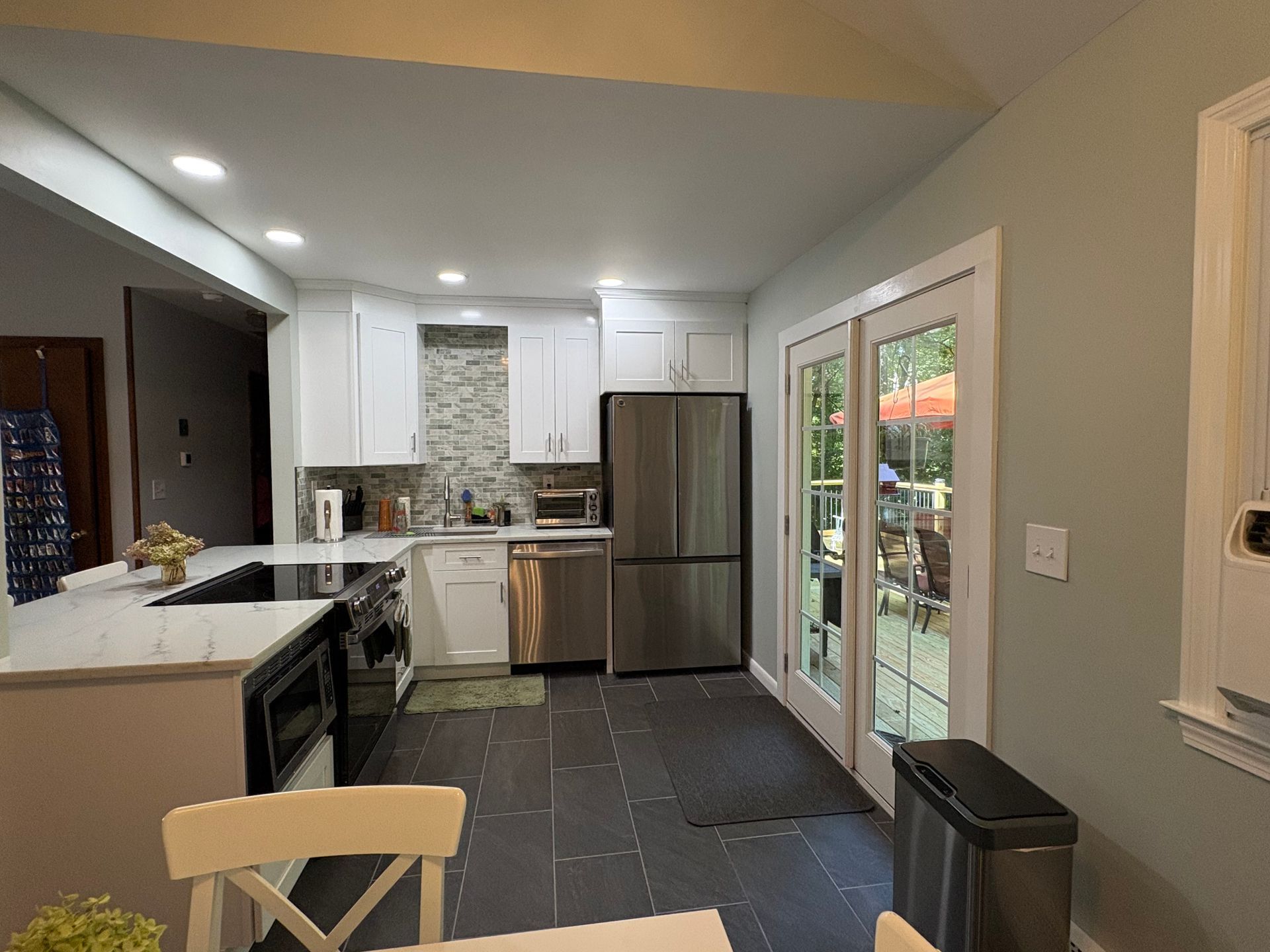 A bright, modern kitchen with white cabinets, stainless steel appliances, and a view of the backyard.
