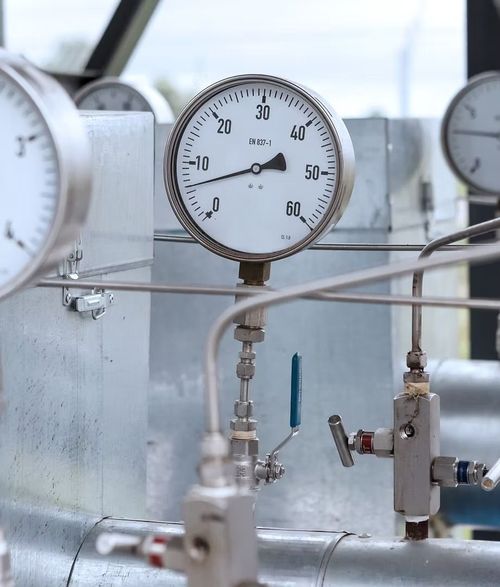 Analog gauge on industrial piping and valves in a lab or factory setting