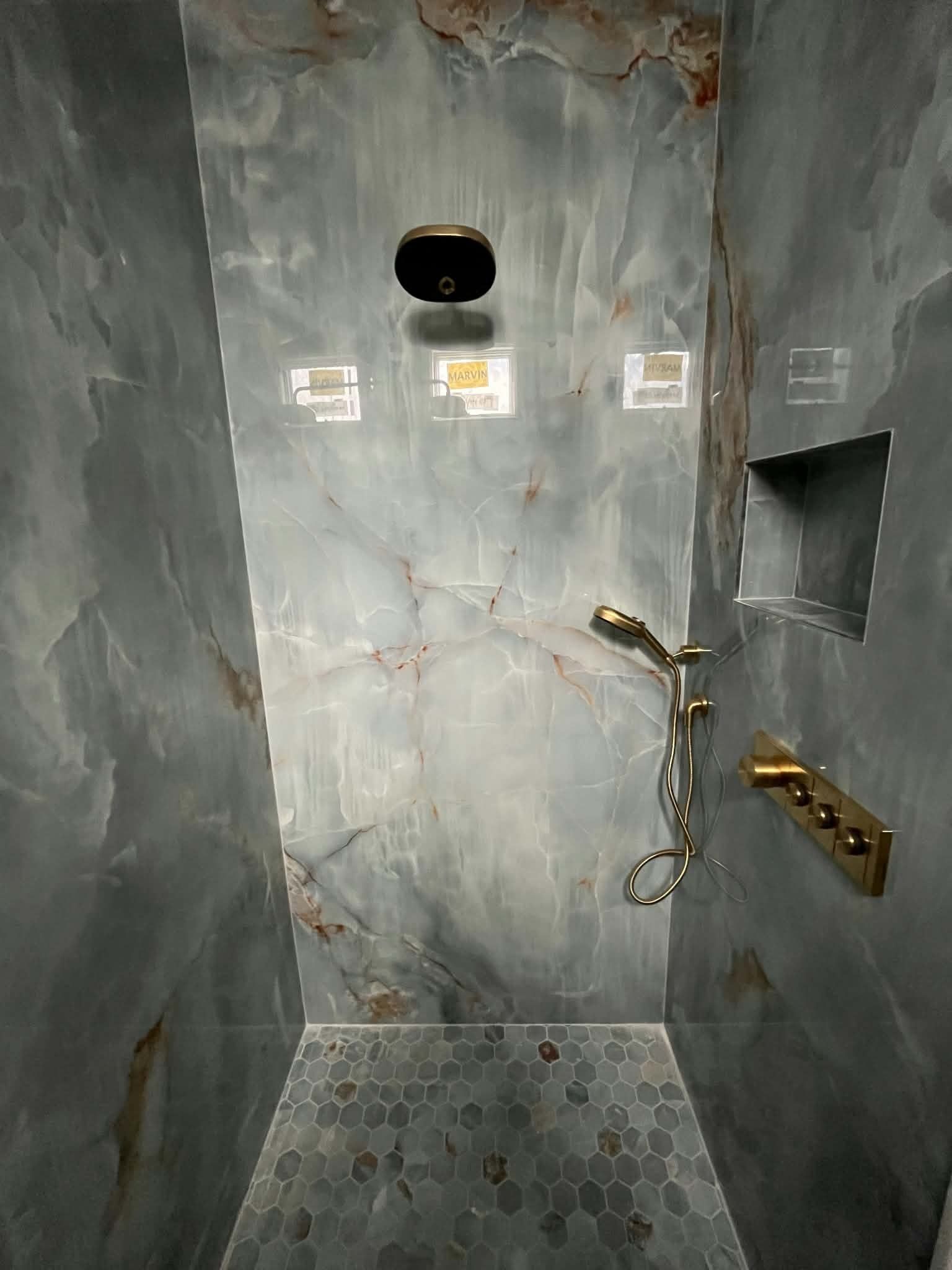 Modern gray-tiled shower stall with wall-mounted fixtures and handheld showerhead