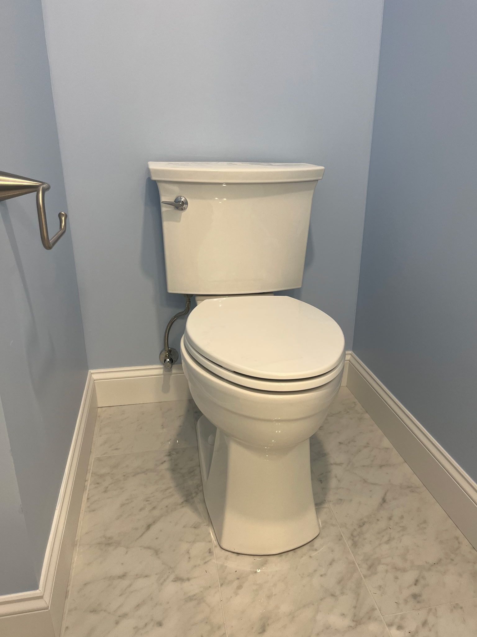 Small bathroom with a white toilet against light blue walls and marble-patterned floor.