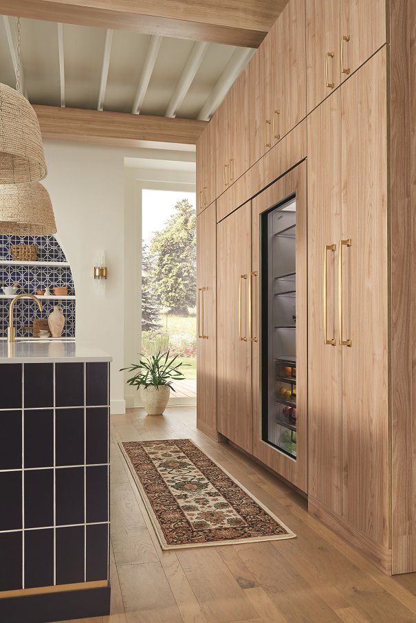 A kitchen with wooden cabinets , a rug , and a refrigerator.