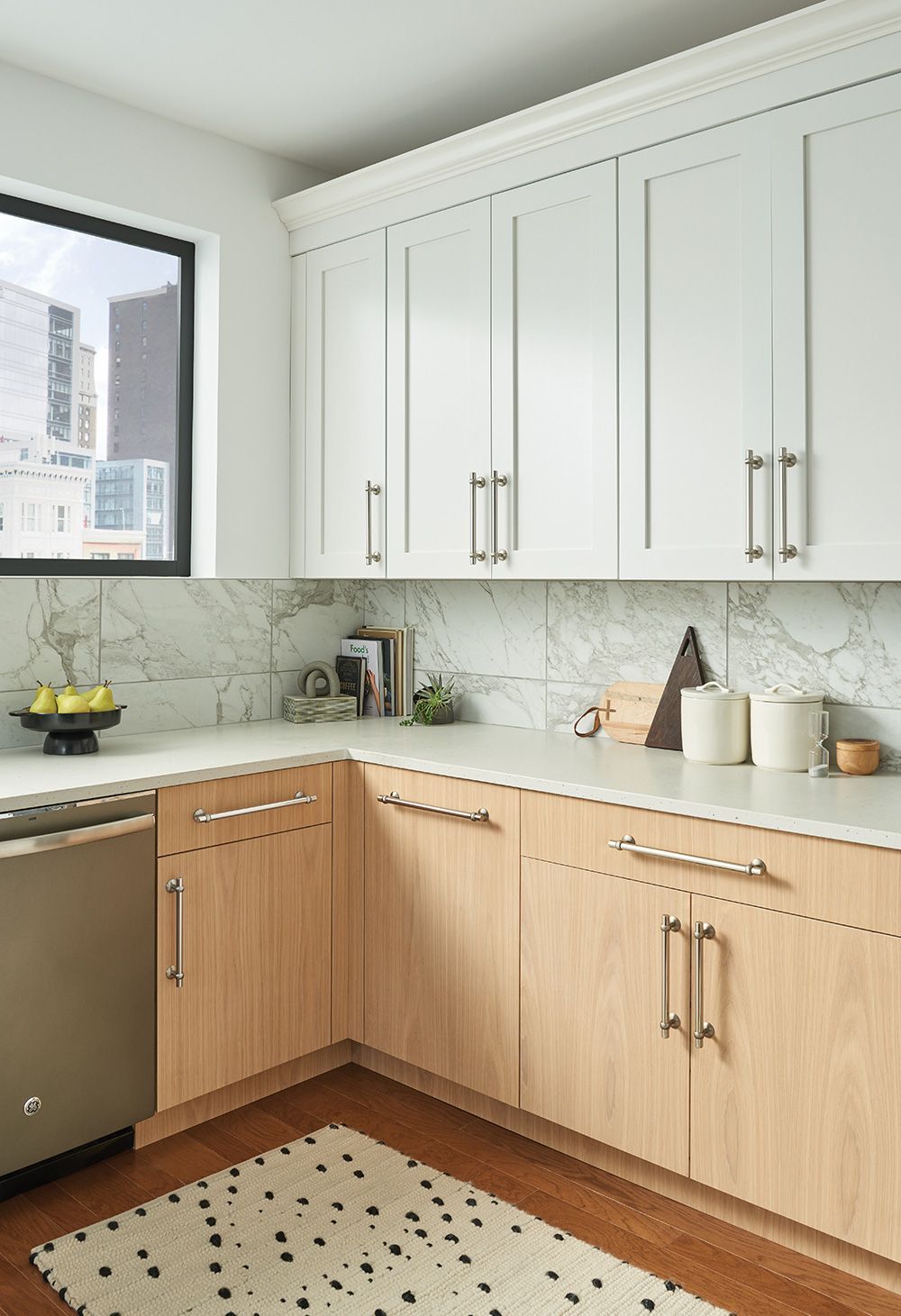 A kitchen with white cabinets and wooden cabinets and a rug on the floor.