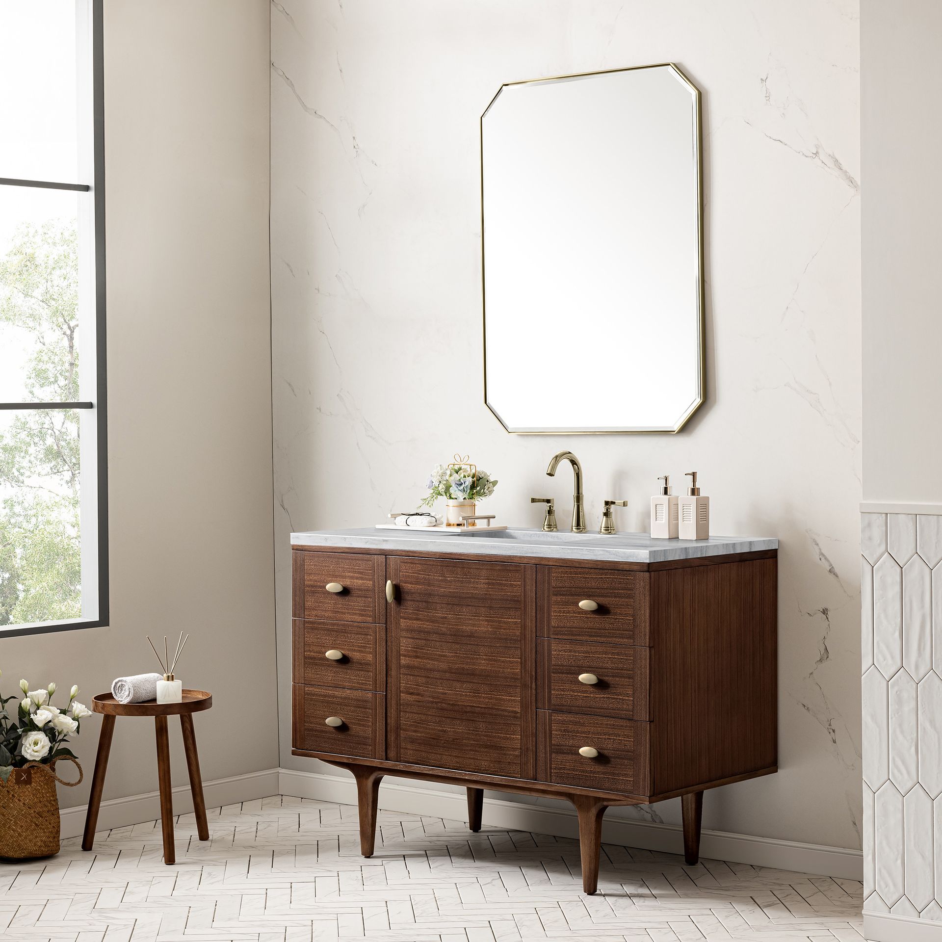 A bathroom with a wooden vanity , sink , mirror and stool.