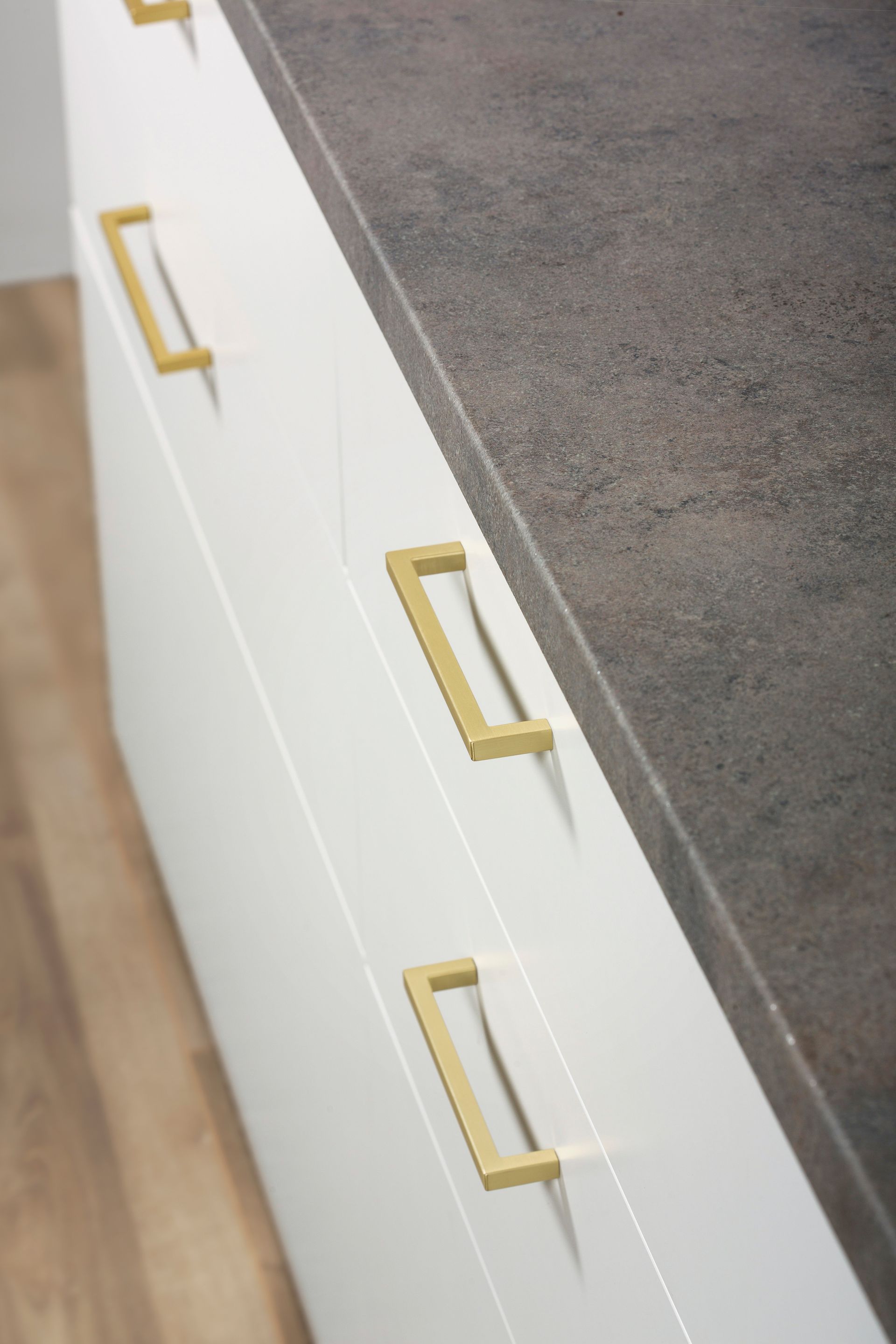 A close up of a kitchen counter with white cabinets and gold handles.