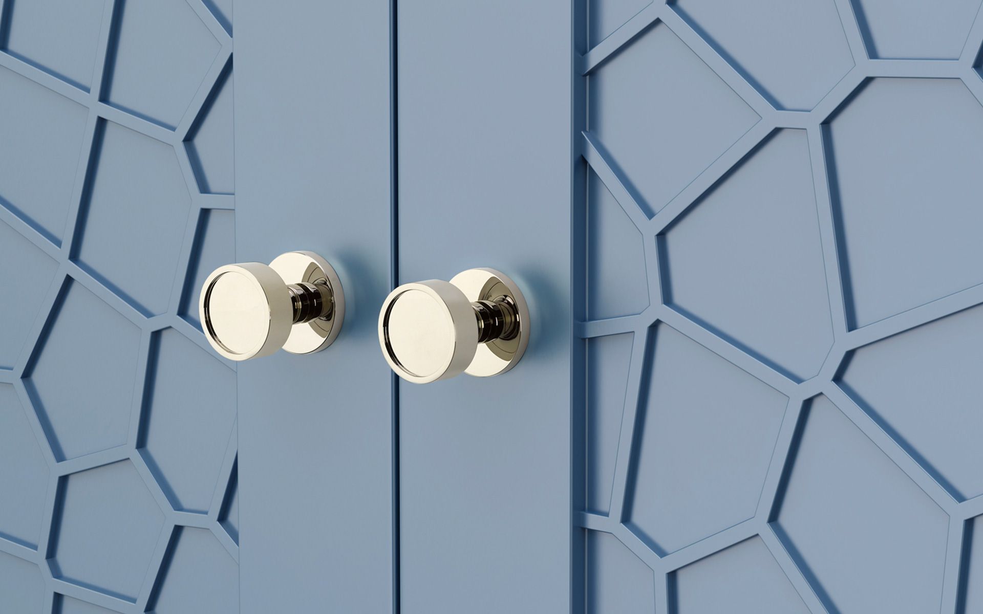A close up of a blue cabinet with a geometric pattern and brass handles.