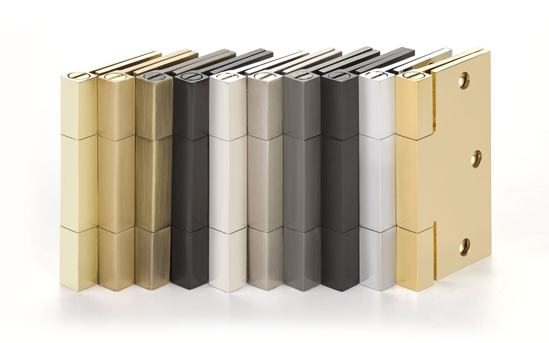 A bunch of different colored door hinges are stacked on top of each other on a white surface.