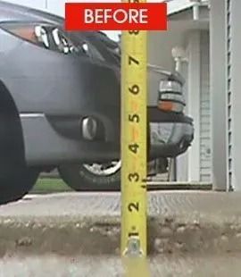 A tape measure shows the height of a concrete surface in front of a car.  