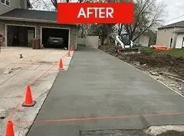 Newly poured concrete driveway with orange cones and construction equipment. 
