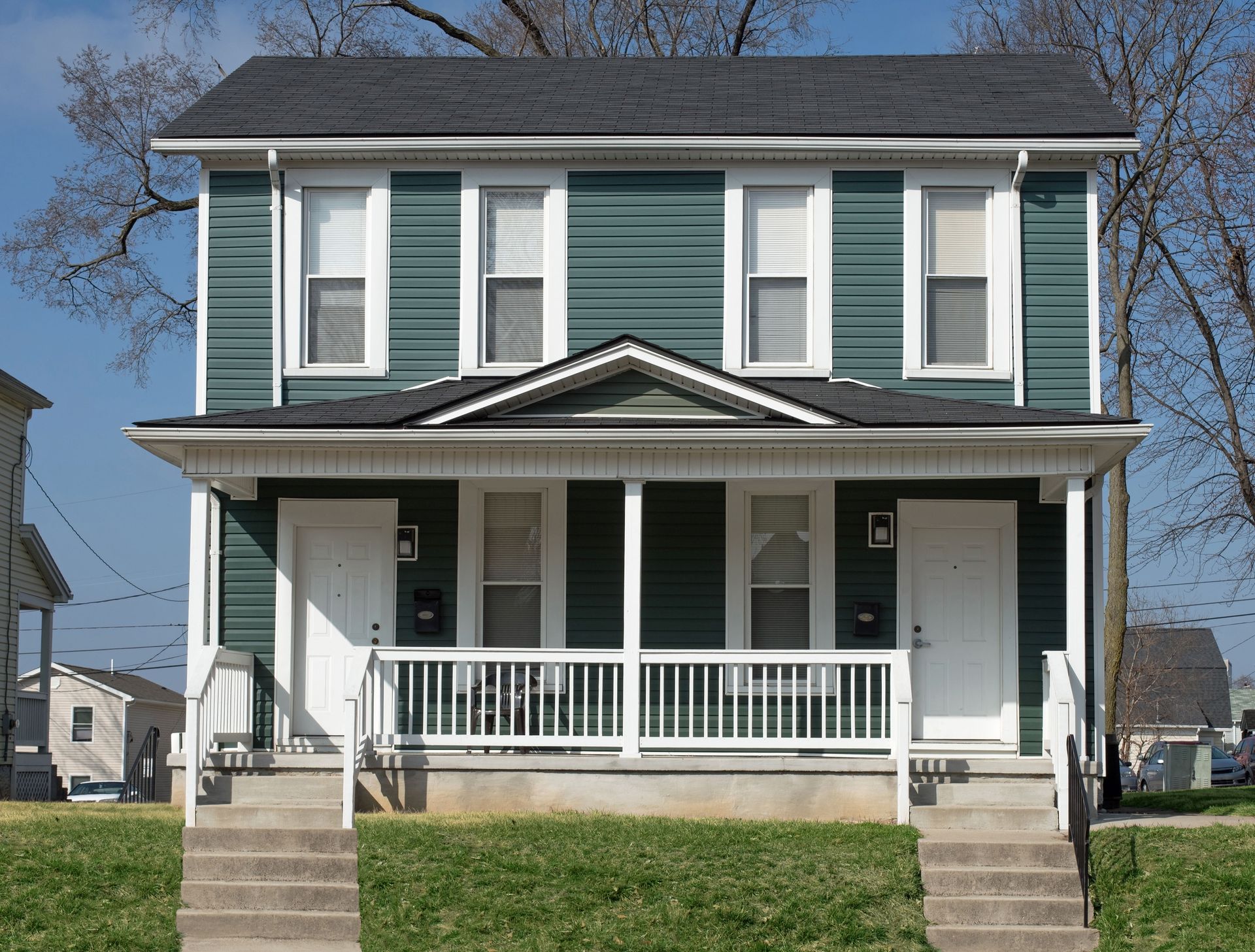 A green and white house with a porch and stairs