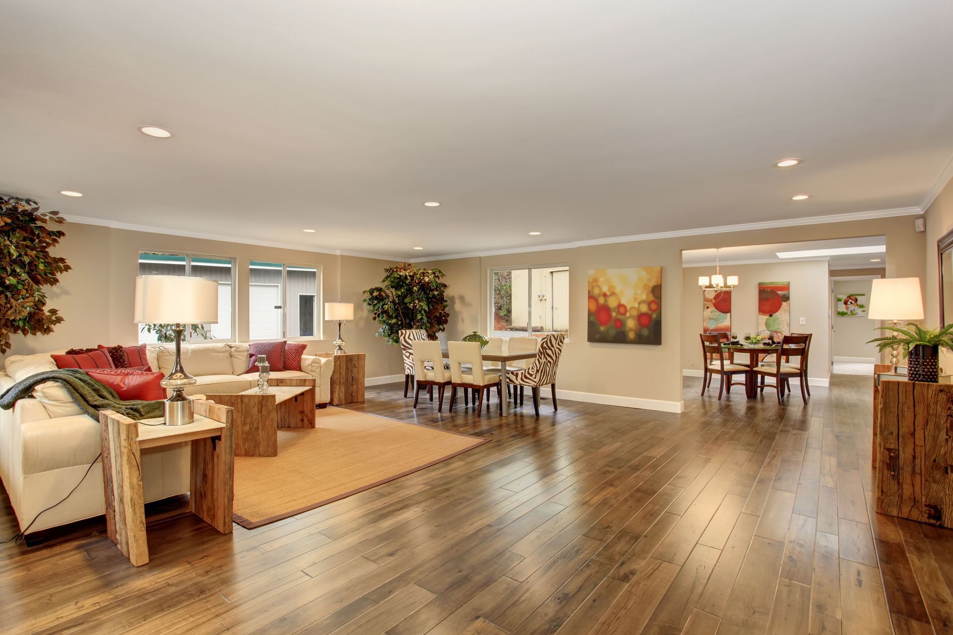 A living room with hardwood floors and a dining room in the background.