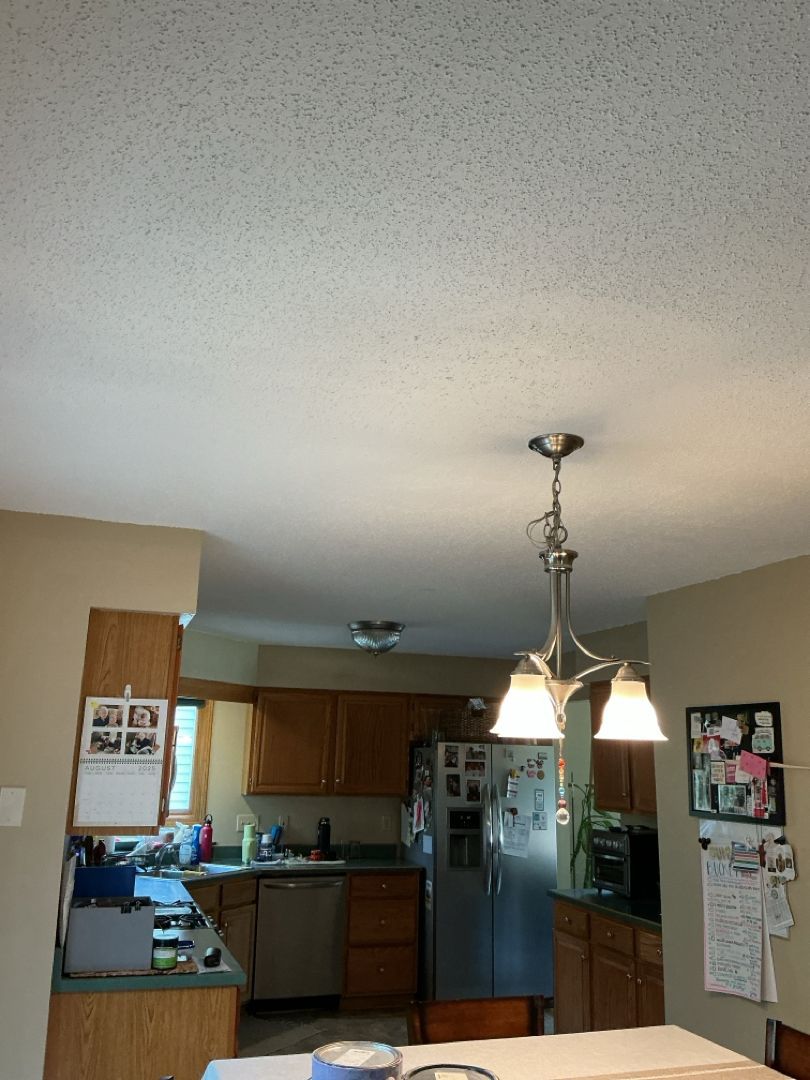 Kitchen with popcorn ceiling, wooden cabinets, stainless steel refrigerator, and chandelier.