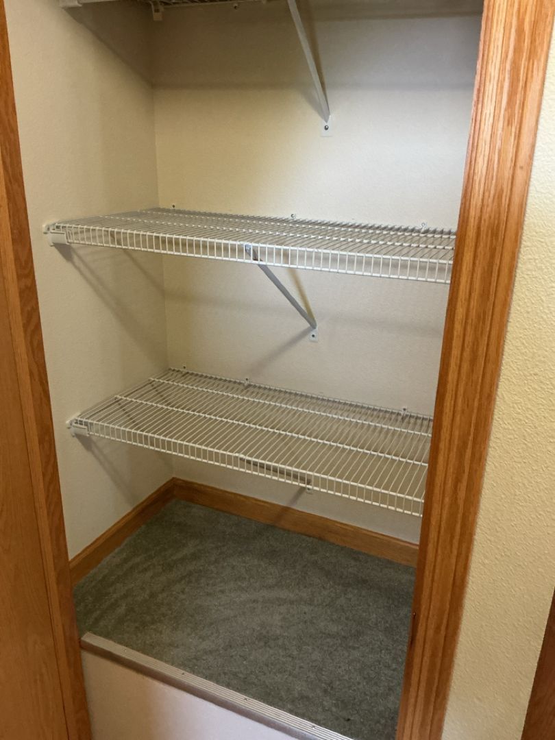 Empty closet with wire shelves and carpeted floor.