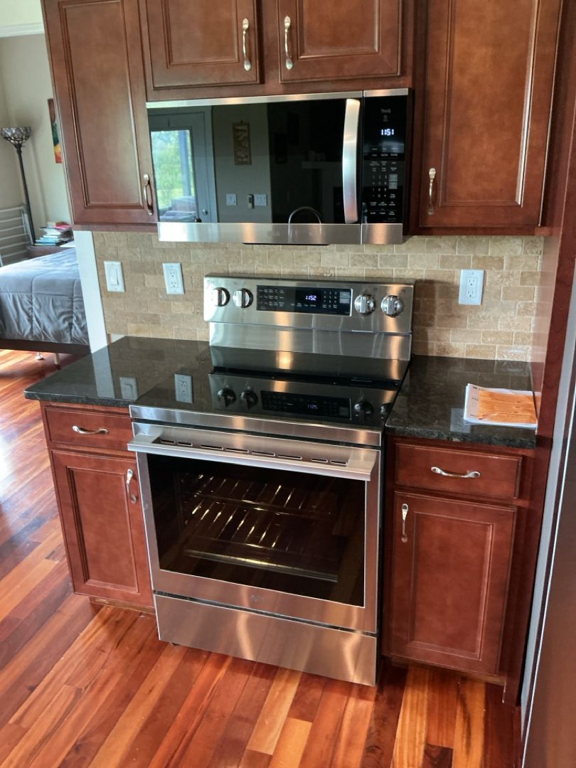 Kitchen with stainless steel oven and microwave, dark cabinets, and granite countertop.