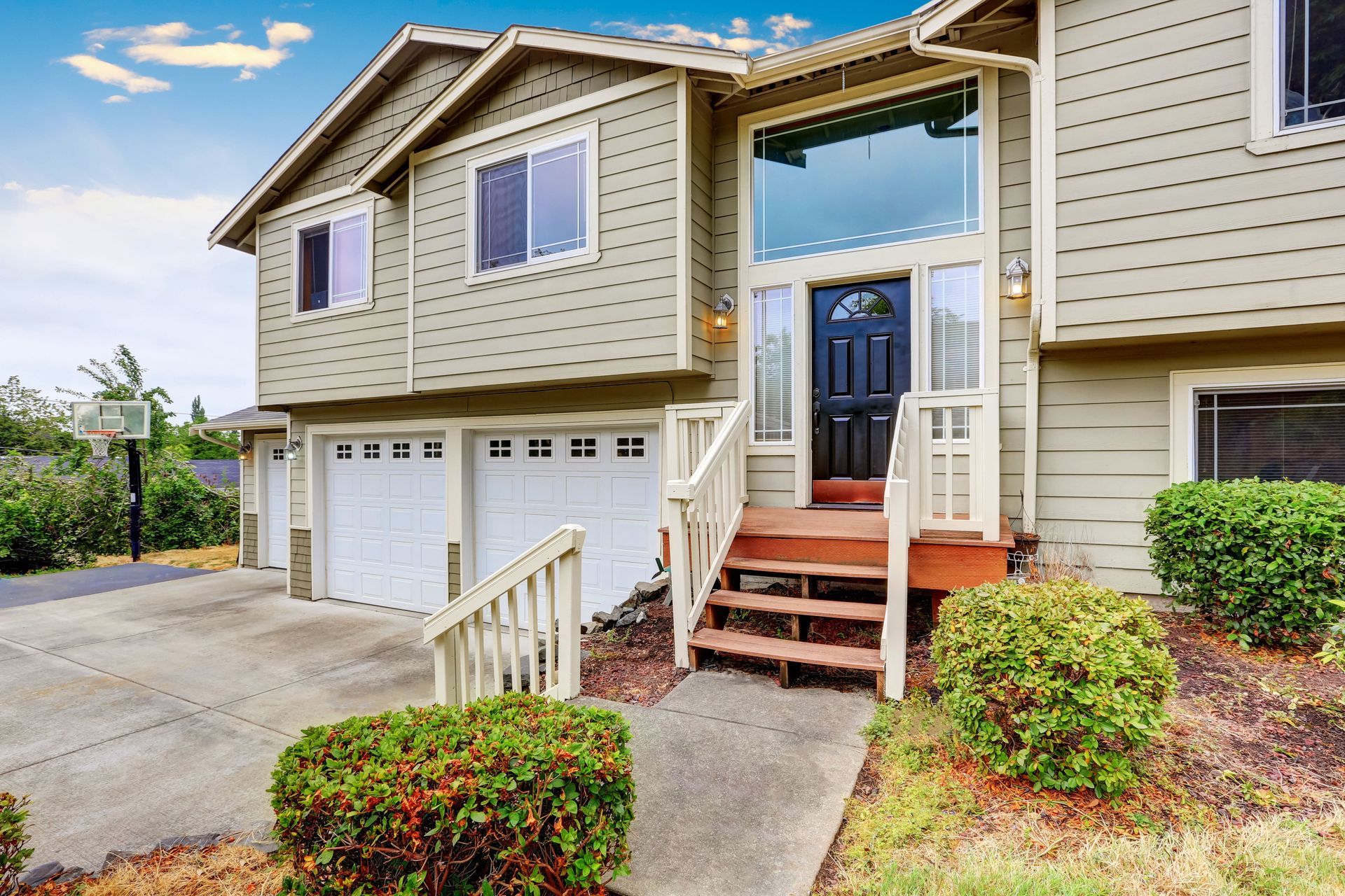 A large house with two garages and stairs leading up to the front door.