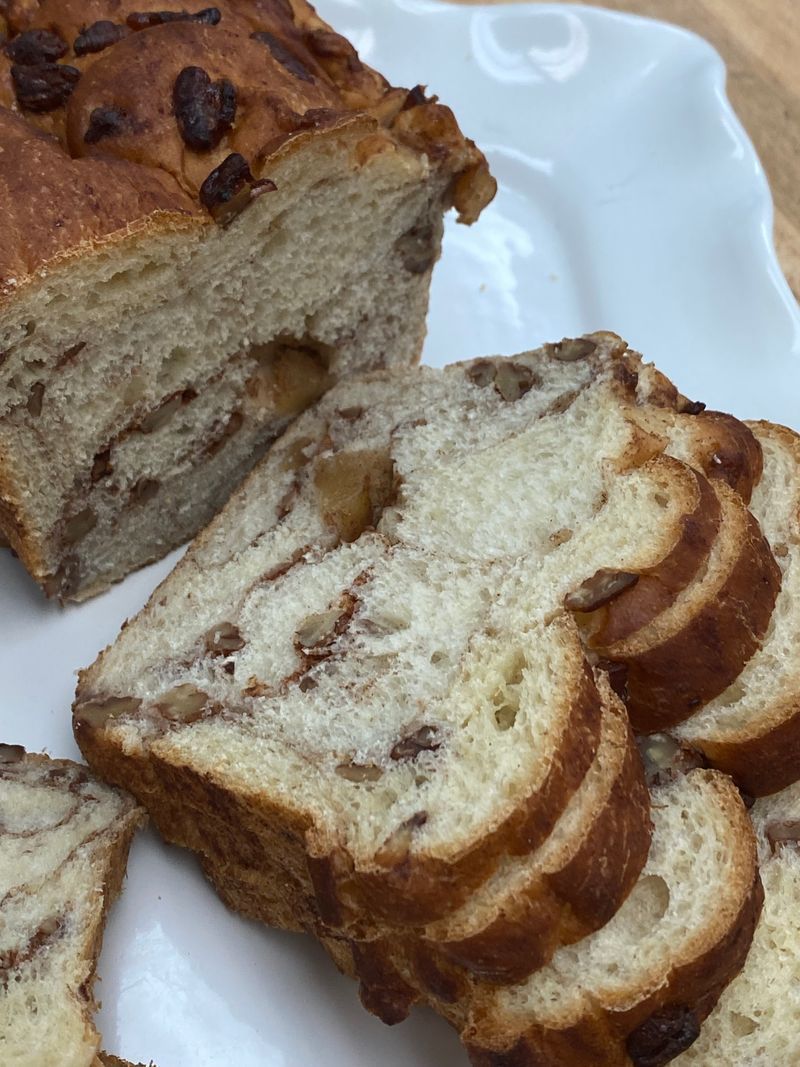 A loaf of sliced cinnamon raisin bread on a white platter.
