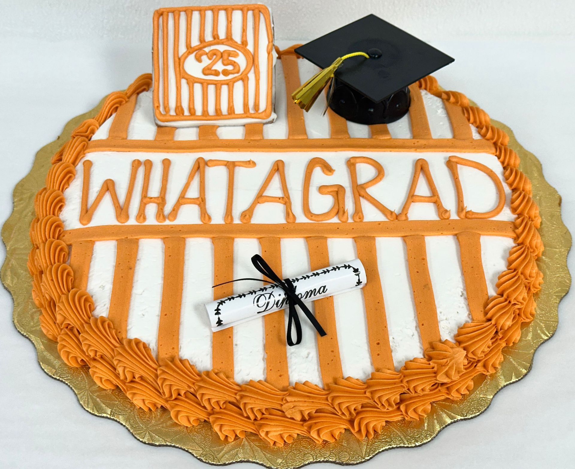 Orange-and-white graduation cake with WHATAGRAD lettering and a black mortarboard topper