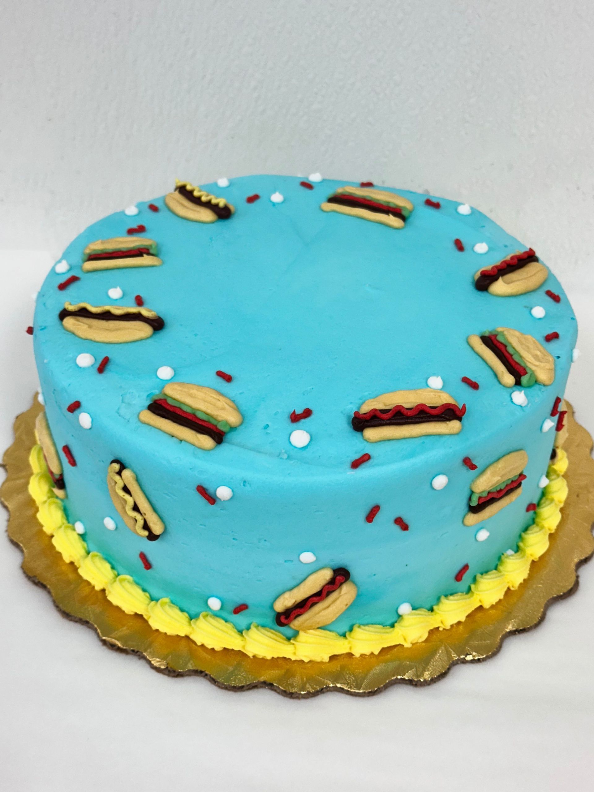 Blue frosted round cake with gold trim and small chocolate-striped decorations