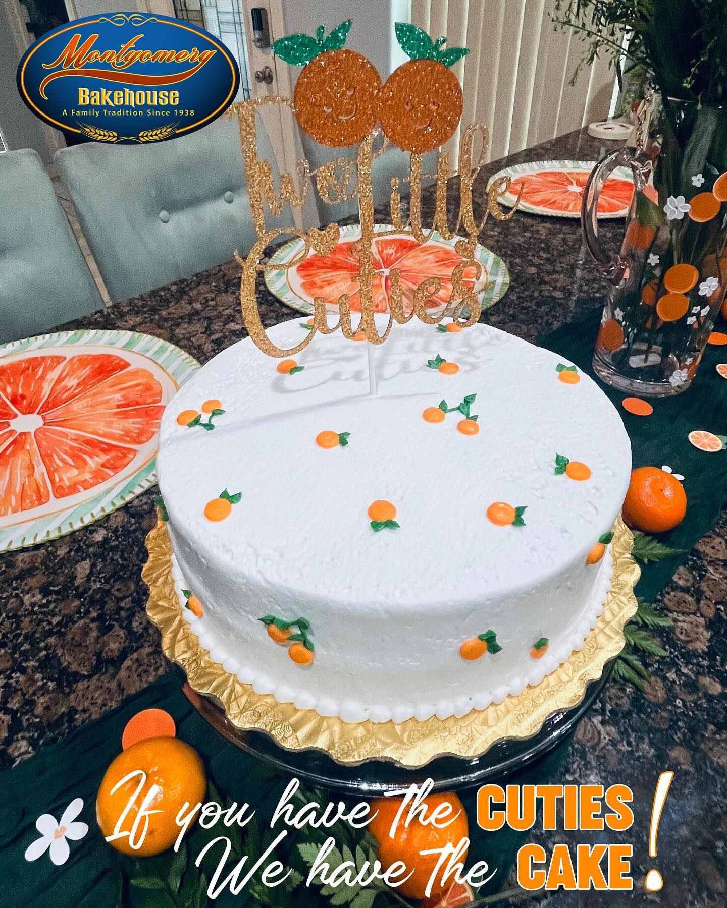White cake decorated with orange cuties and a gold 