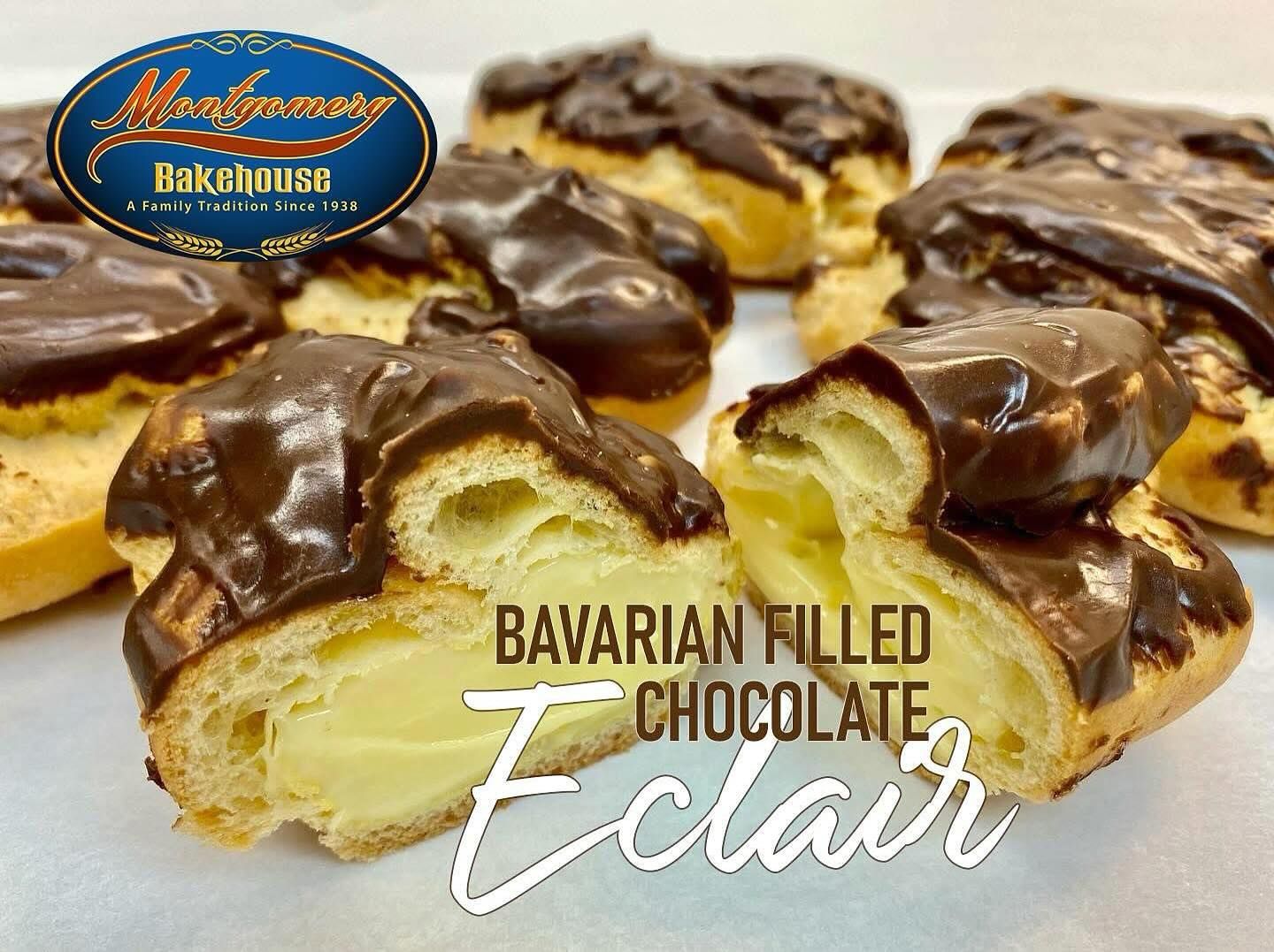 Bavarian-filled chocolate eclair, cut to show creamy filling, topped with dark chocolate glaze, bakery setting.