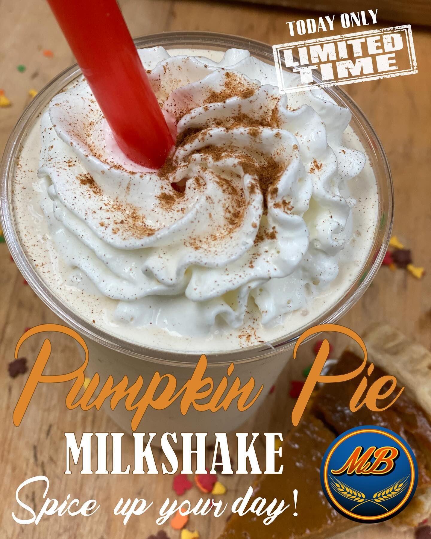 Pumpkin Pie Milkshake with whipped cream and cinnamon, red straw, on wood.
