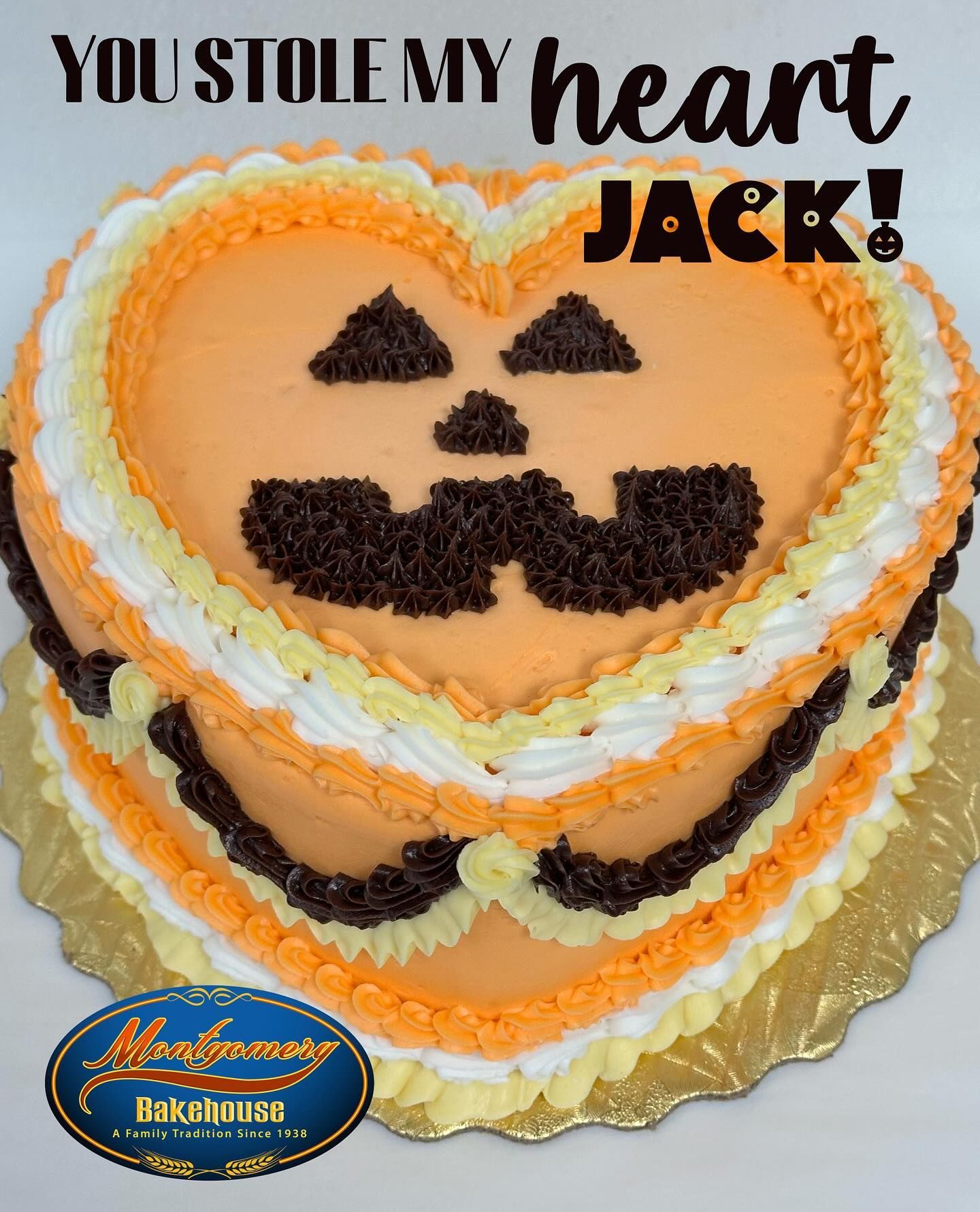 Heart-shaped Jack-o'-lantern cake with text. Orange icing, chocolate details.