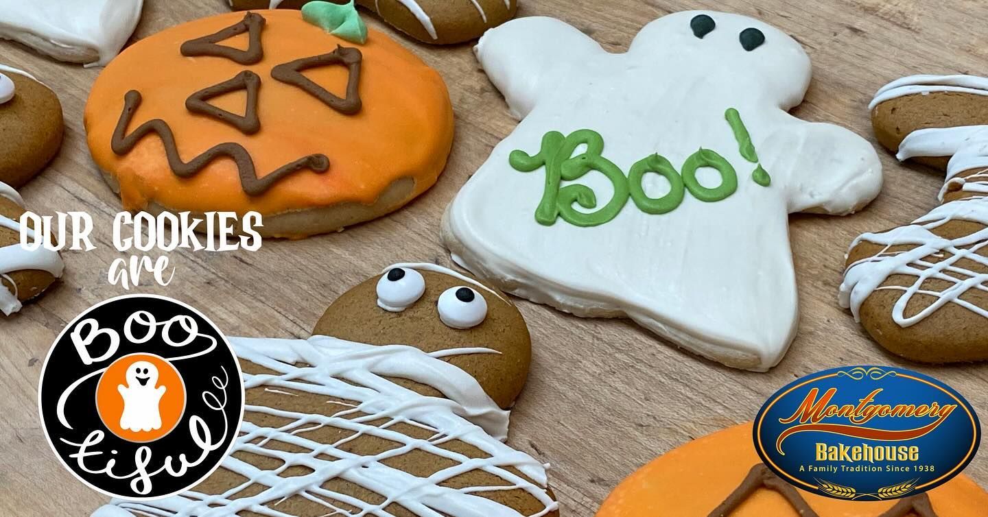 Halloween cookies decorated as a pumpkin, ghost, and mummy; wooden surface.