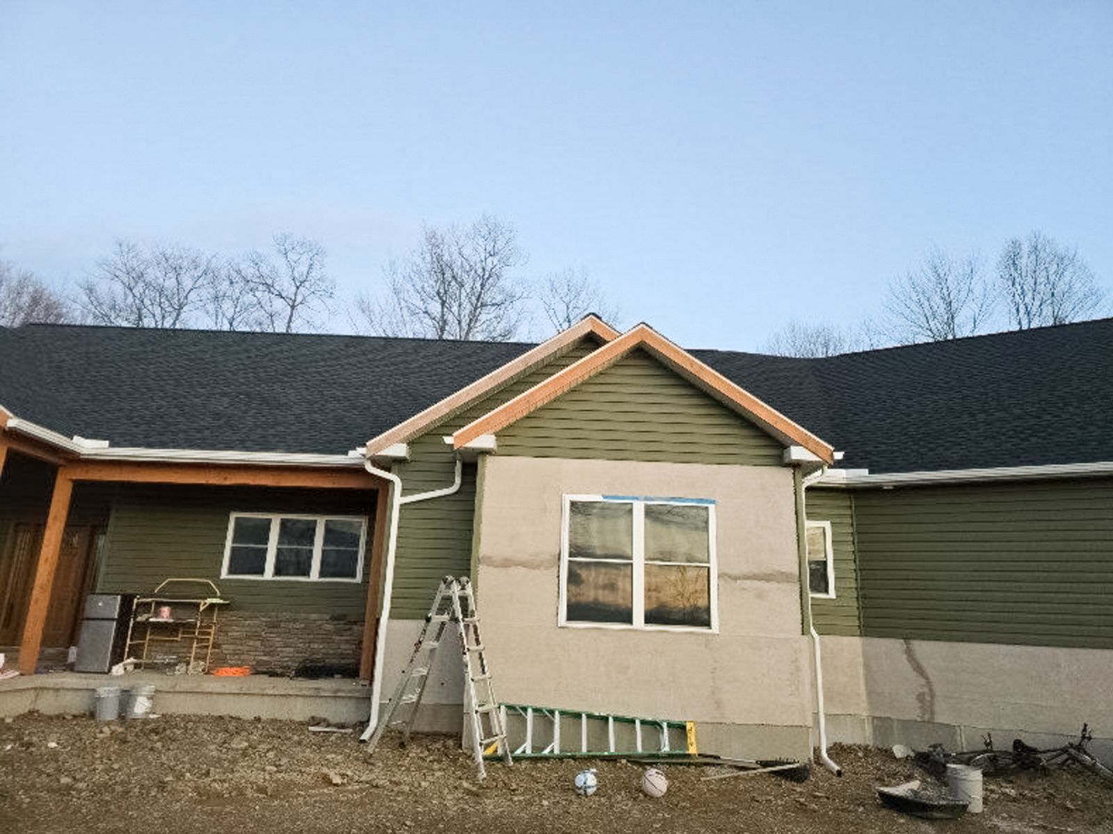 Exterior of a house under renovation with ladder, unfinished siding, and exposed wall sections