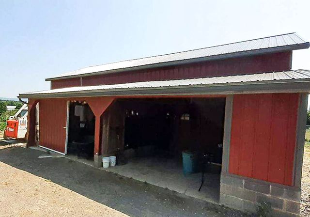 Red barn-style building with open front bays and red siding under a metal roof.
