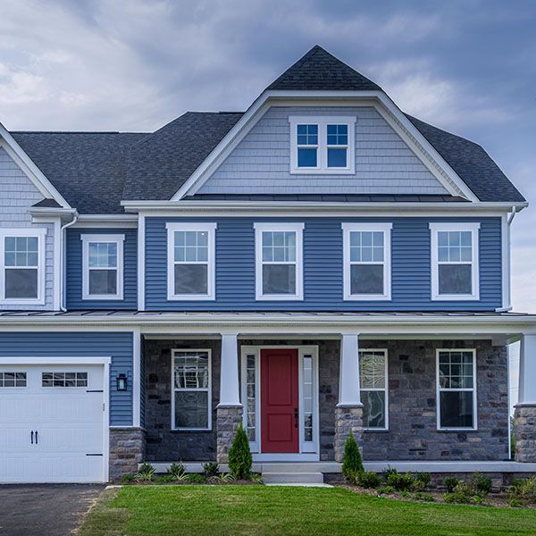 Blue two-story suburban house with white trim, stone accents, red front door, and attached garage