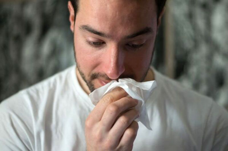 A man is blowing his nose into a napkin