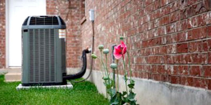 An air conditioner is sitting on the side of a brick building