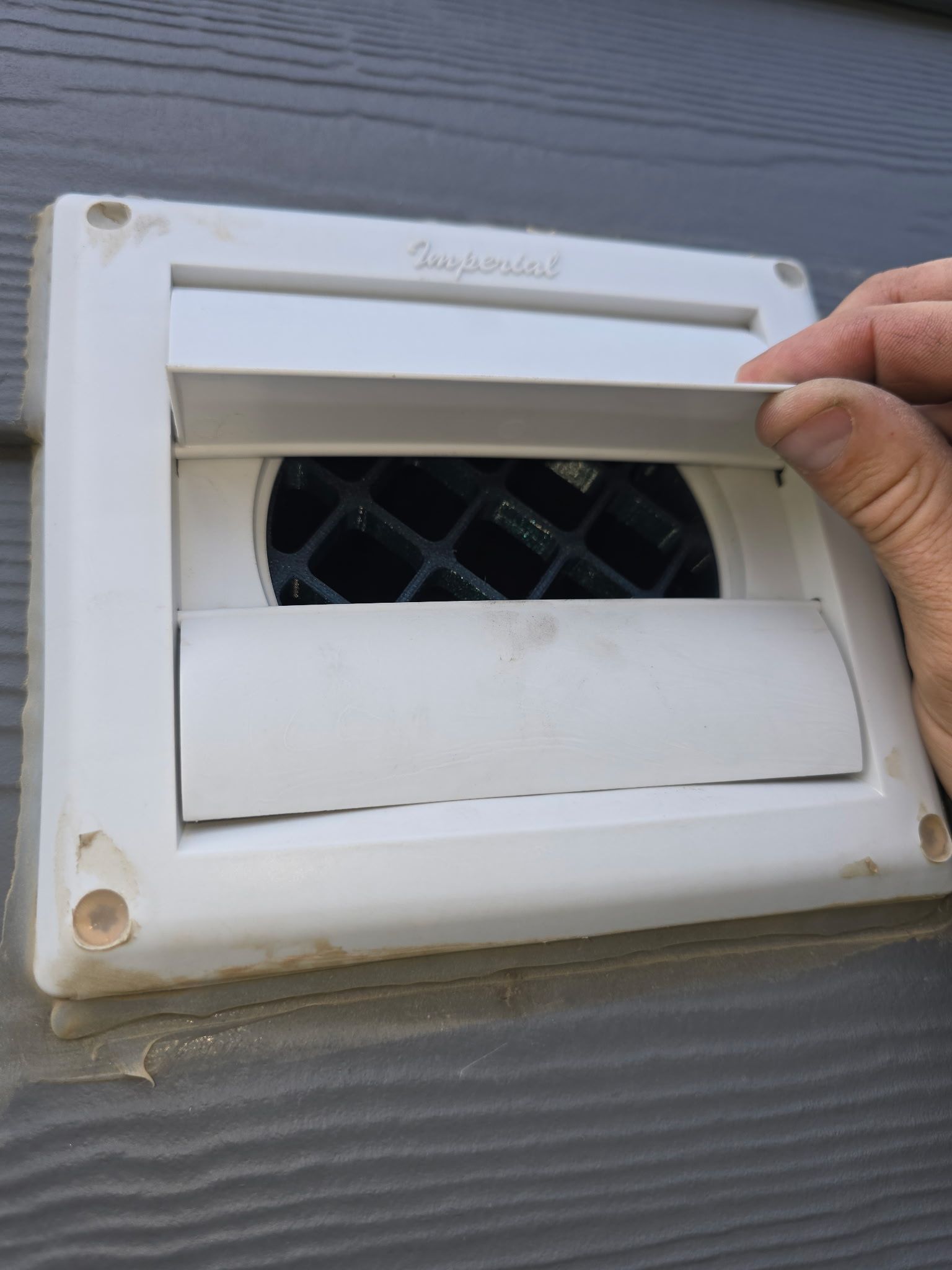A person is opening a vent on a wall